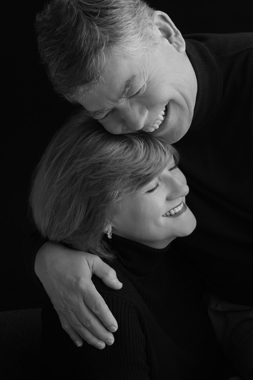 Man leaning over a smiling woman in an embrace, couple portrait in black and white