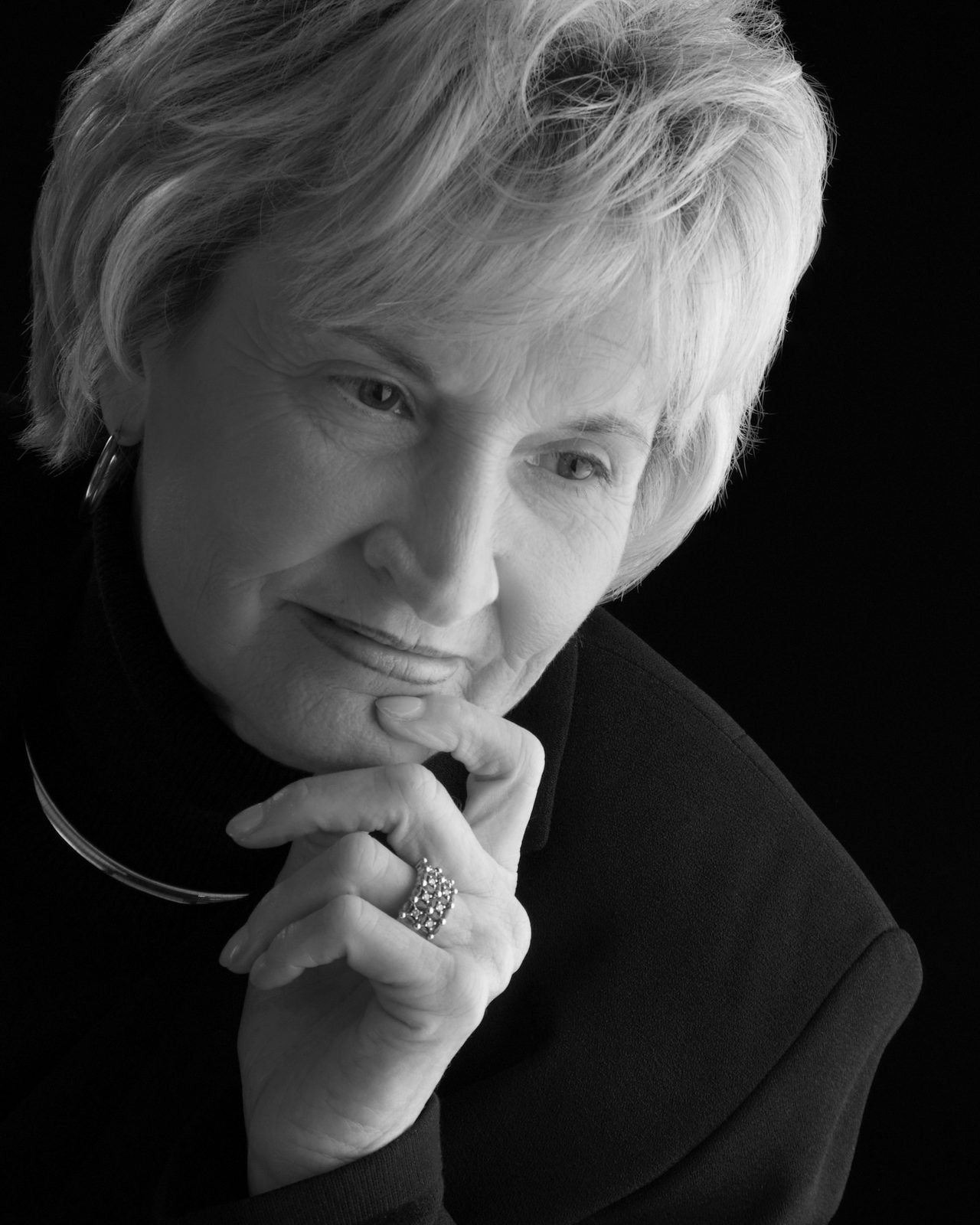 Thoughtful older woman resting her chin on her clasped hands, black and white portrait