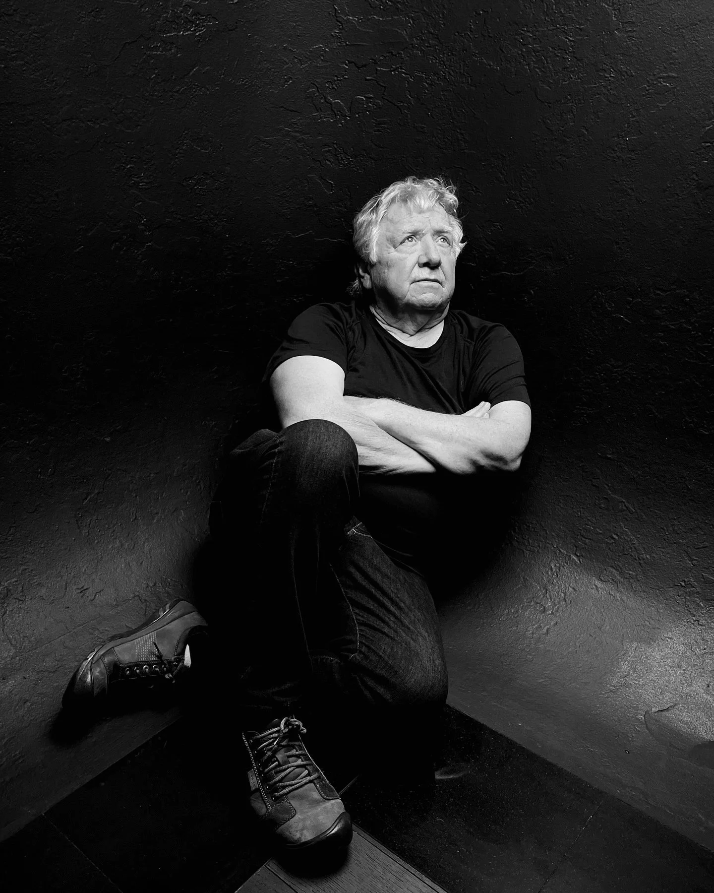 Joe Craig, portrait artist at the House of Soulmarks in Dexter, Missouri, seated with his arms crossed against a dark wall