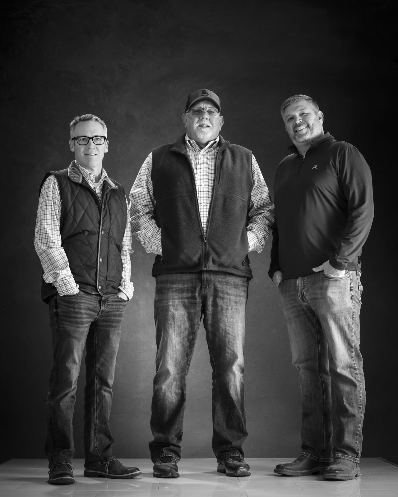 Three farmers standing side by side in a black and white group portrait