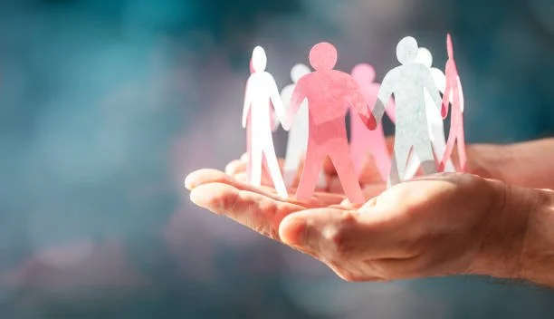 Mani che tengono un cerchio di figure di carta che rappresentano persone, simbolo di comunità e collaborazione.
