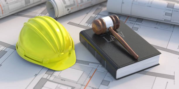 Casco di sicurezza giallo, martello in legno, e libri di architettura su piani di progetto.