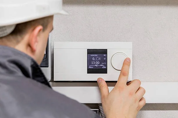Persona che regola un termostato elettronico a parete.