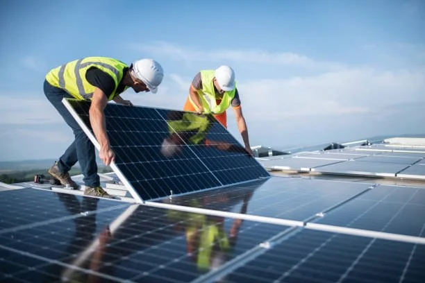 Due lavoratori sui tetti installano pannelli solari.