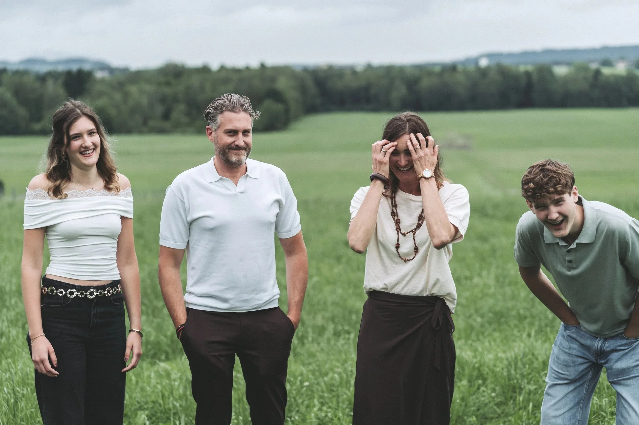 Vier Personen lachen gemeinsam bei einem Gruppenshooting auf einer grünen Wiese in Salzburg – fotografiert von Obi Shenouda Fotografie.