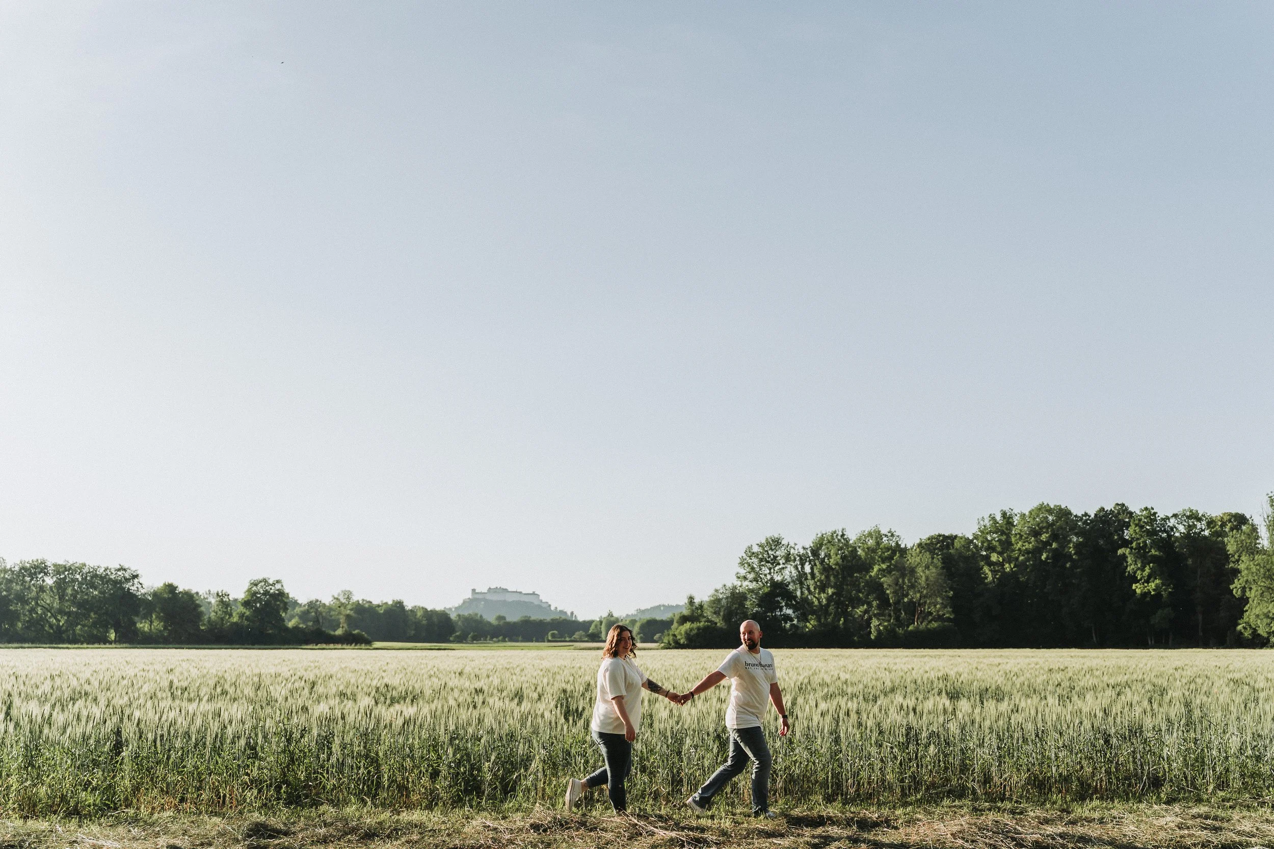 Paar geht Hand in Hand durchs Feld
