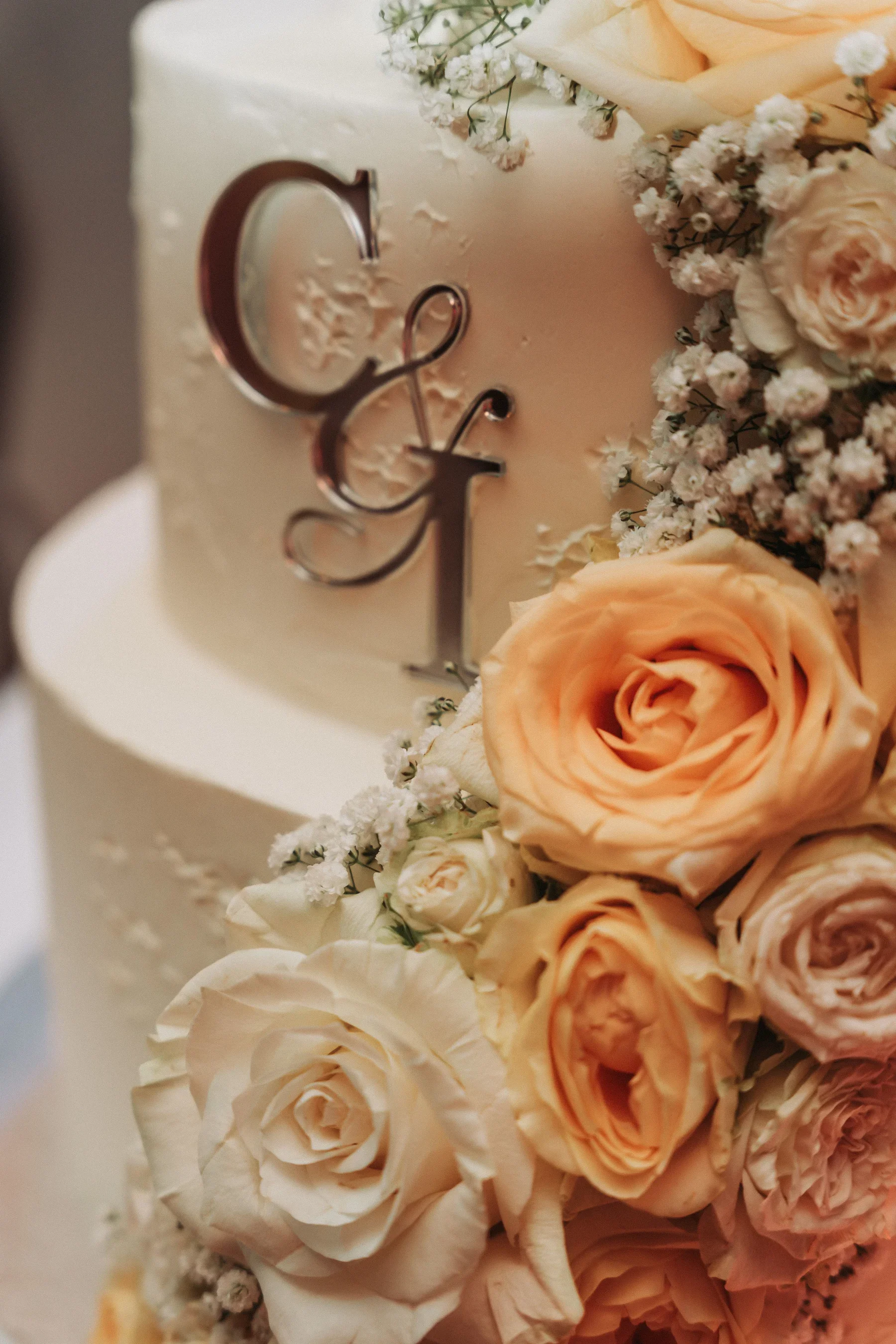 Detail der Hochzeitstorte mit Rosen und Initialen.