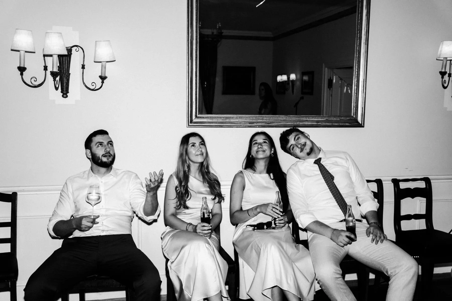 Freunde sitzen gemeinsam im Saal vor dem Hochzeitstanz.
