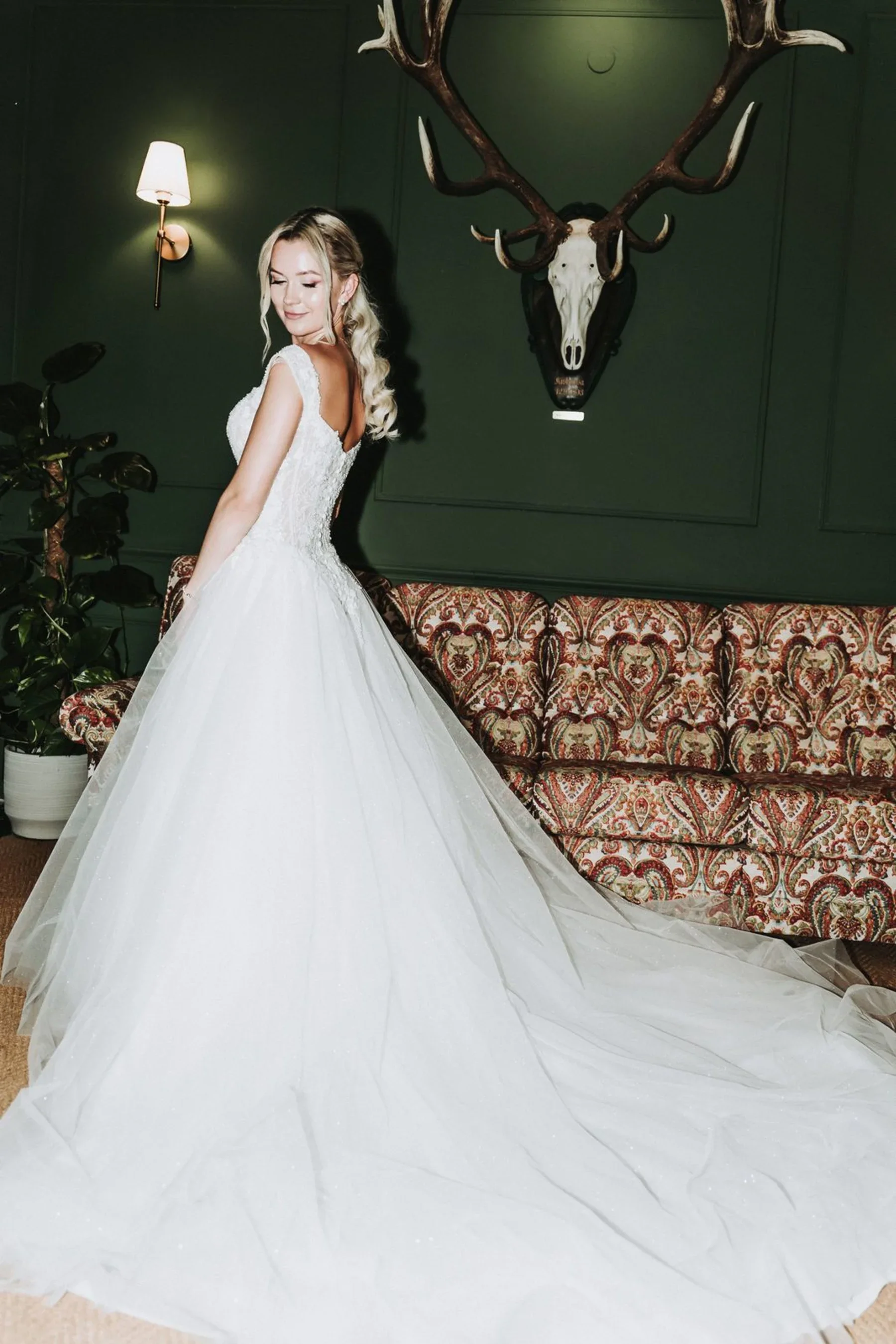 Die Braut zeigt ihr Kleid vor dem Sofa im Schlosswirt.