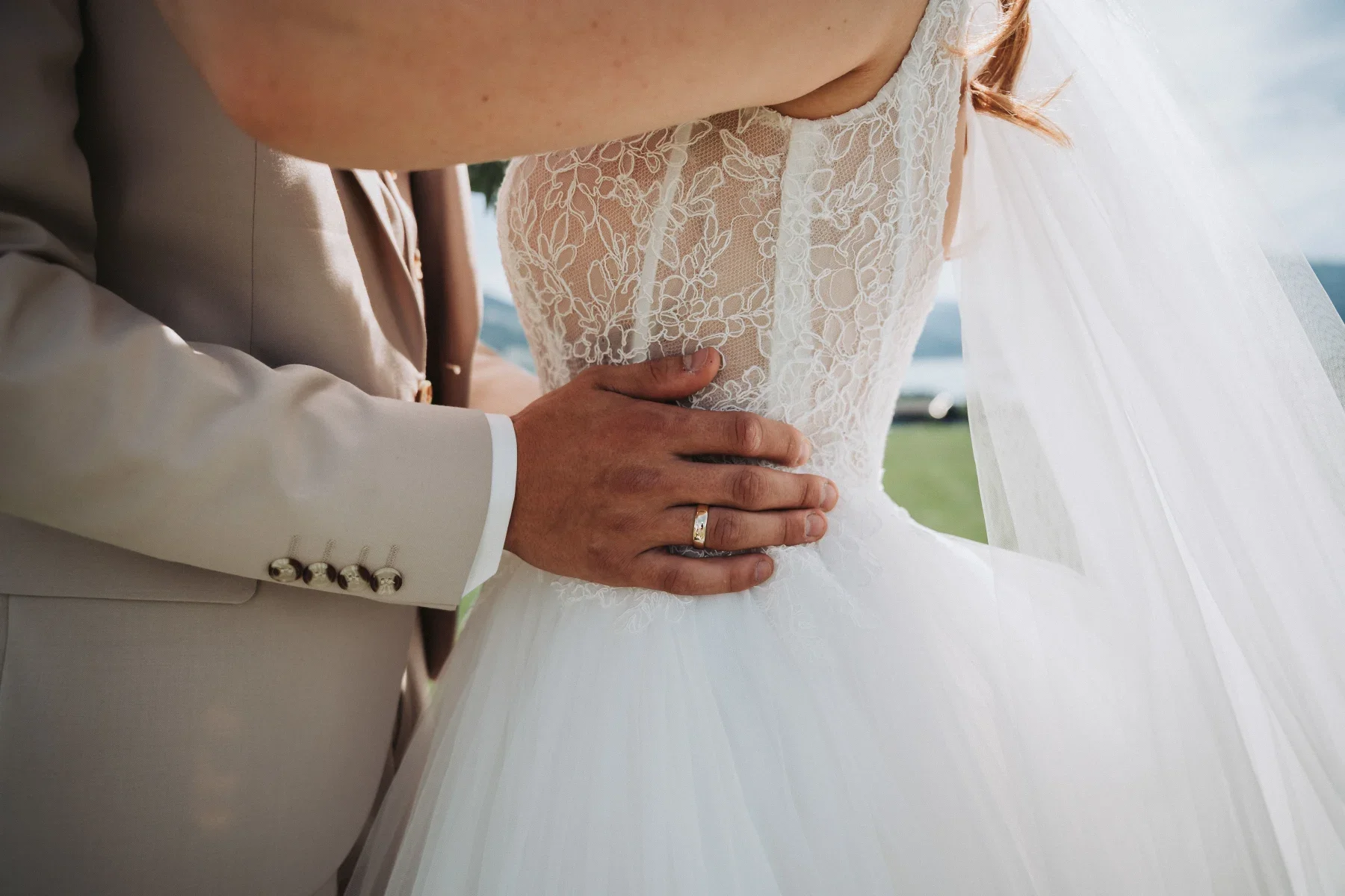 Nahaufnahme einer Umarmung im Brautkleid.
