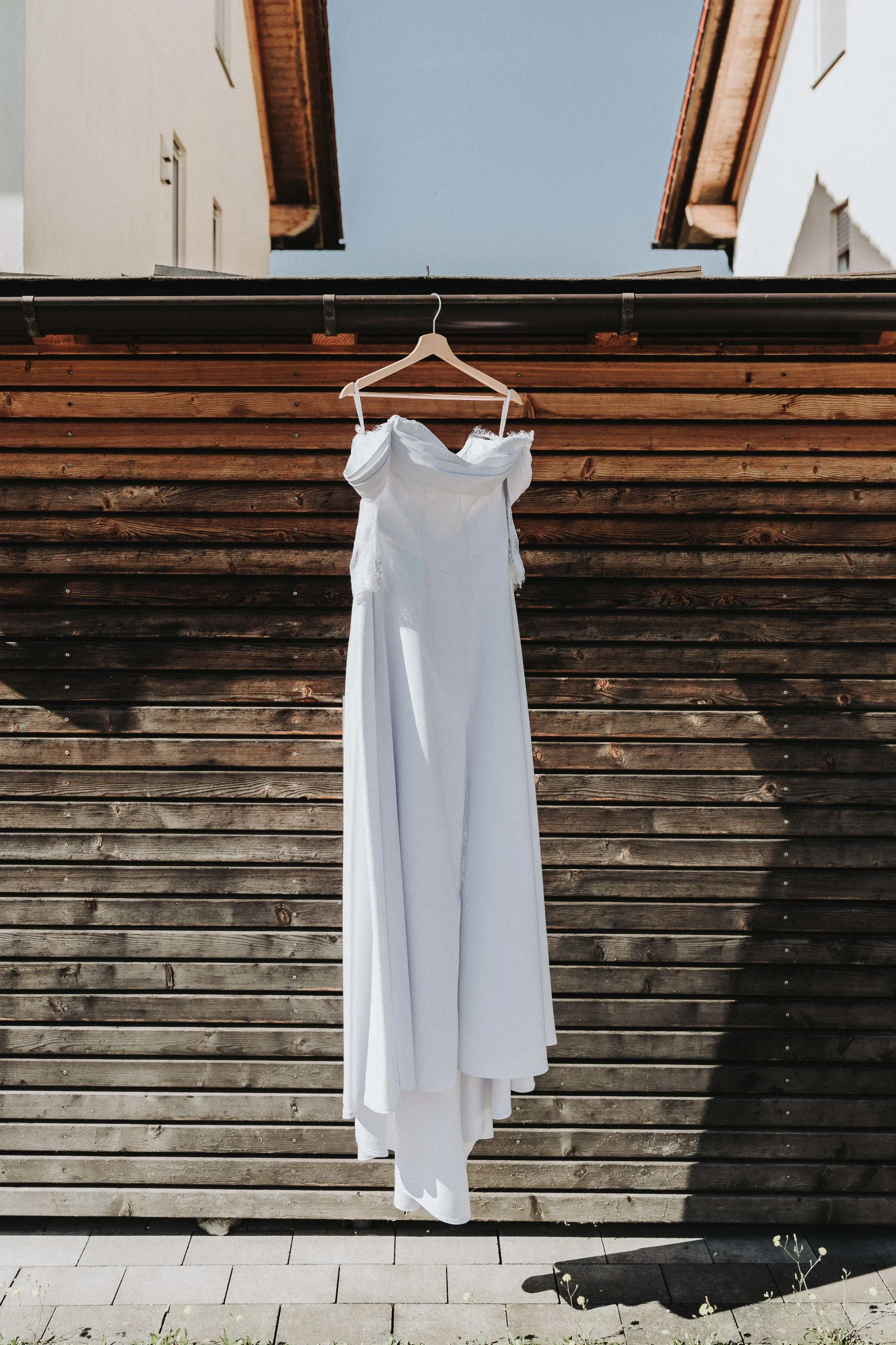 Das Brautkleid hängt vor einer Holzwand.