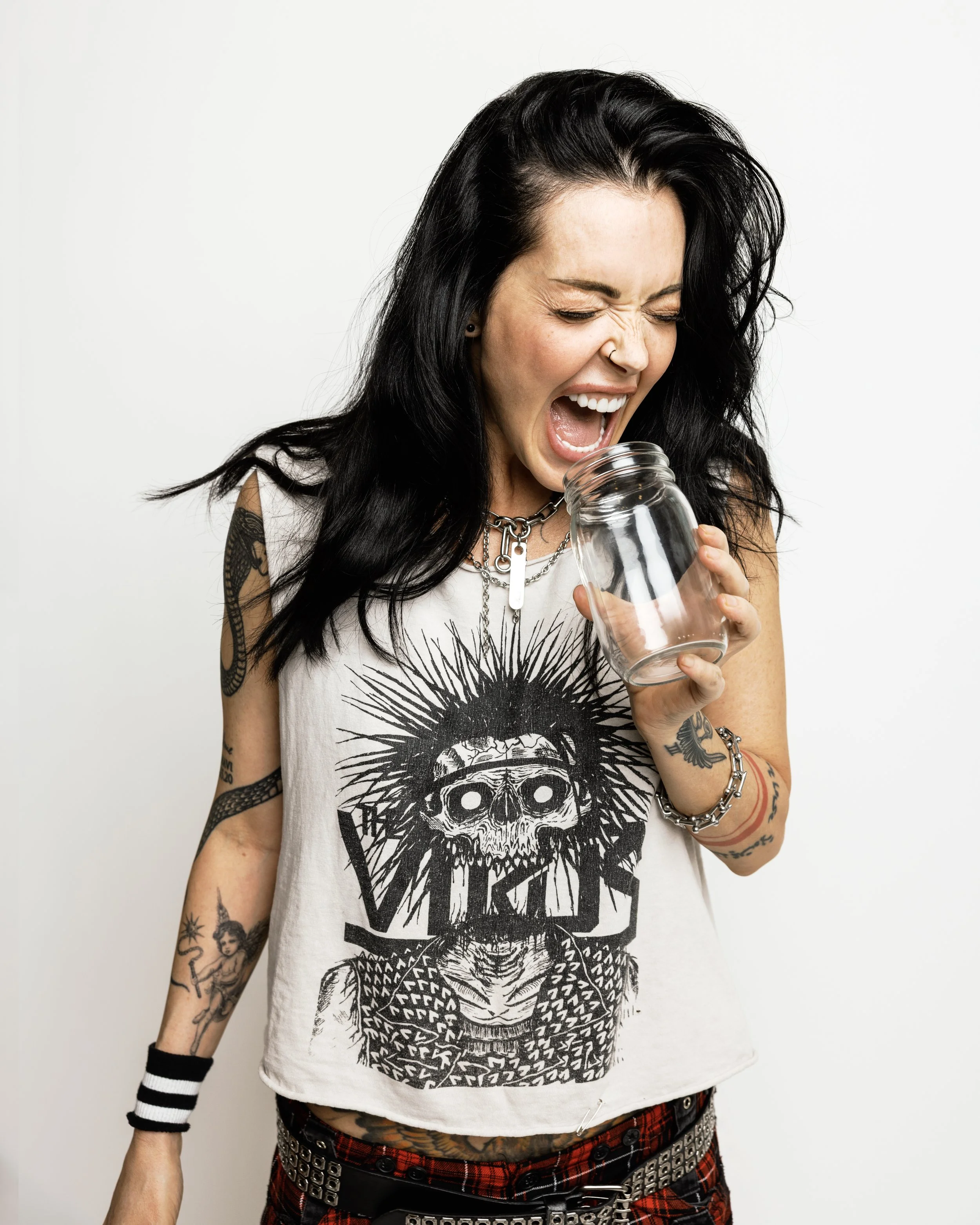A punk rock woman yelling into a glass mason jar.