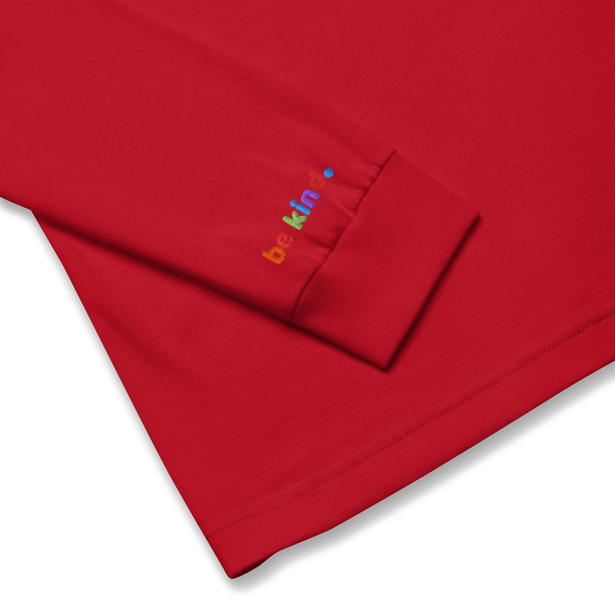 Folded red long sleeve tee with the rainbow be kind embroidered on the wrist cuff
