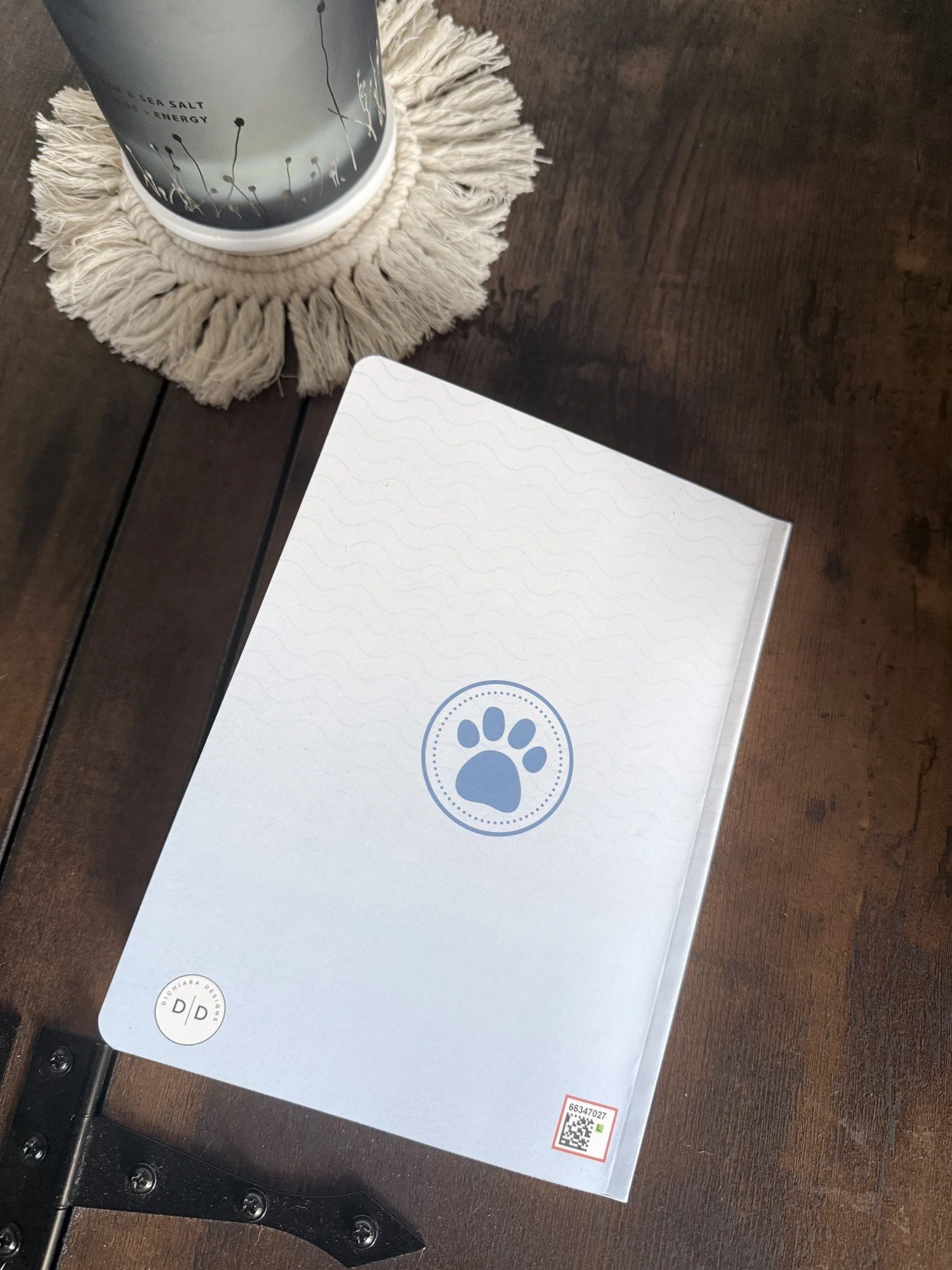 Back cover of the Be Kind journal with a blue paw print medallion and small DiChiara Designs logo