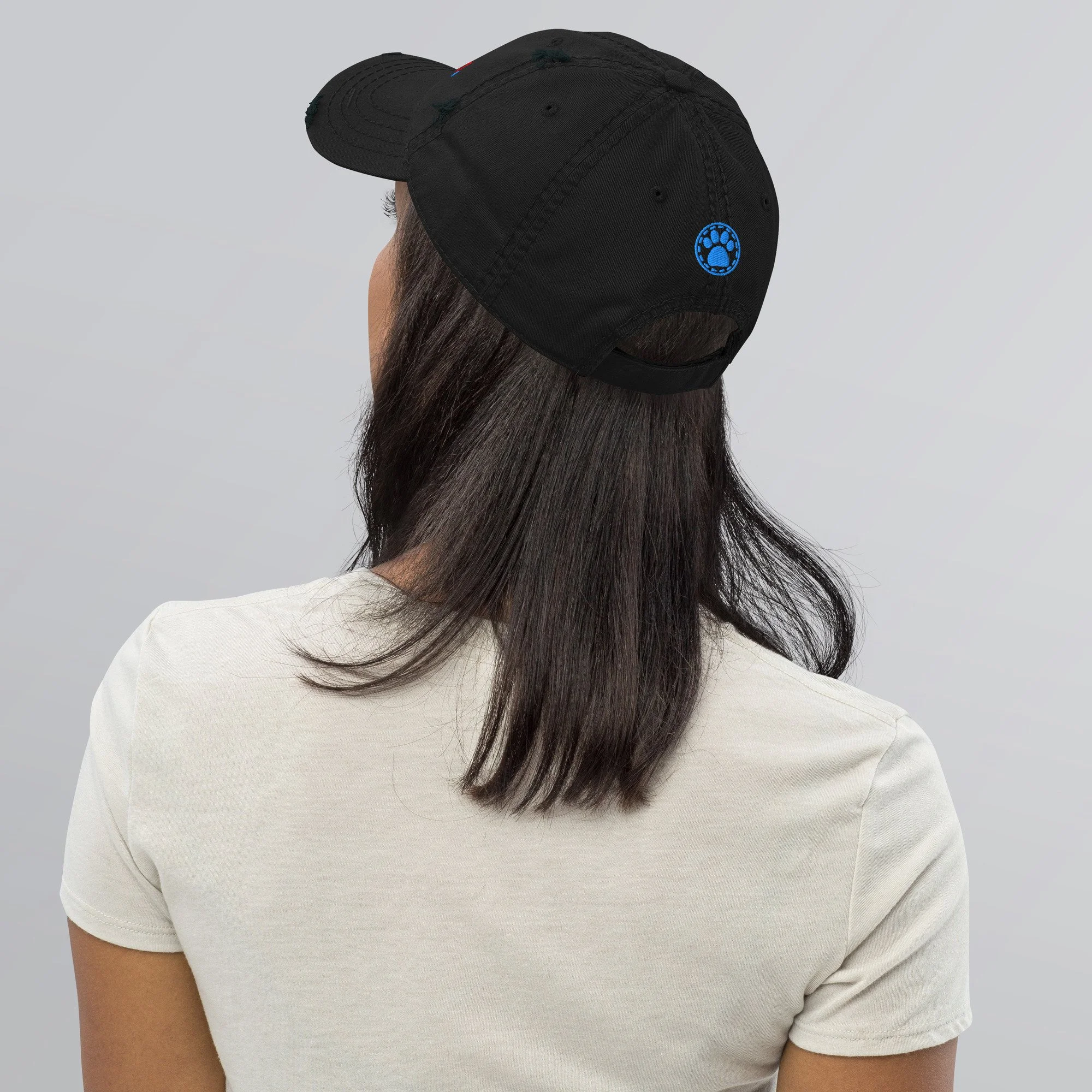 Woman seen from behind wearing the black dad hat, paw print showing at the back