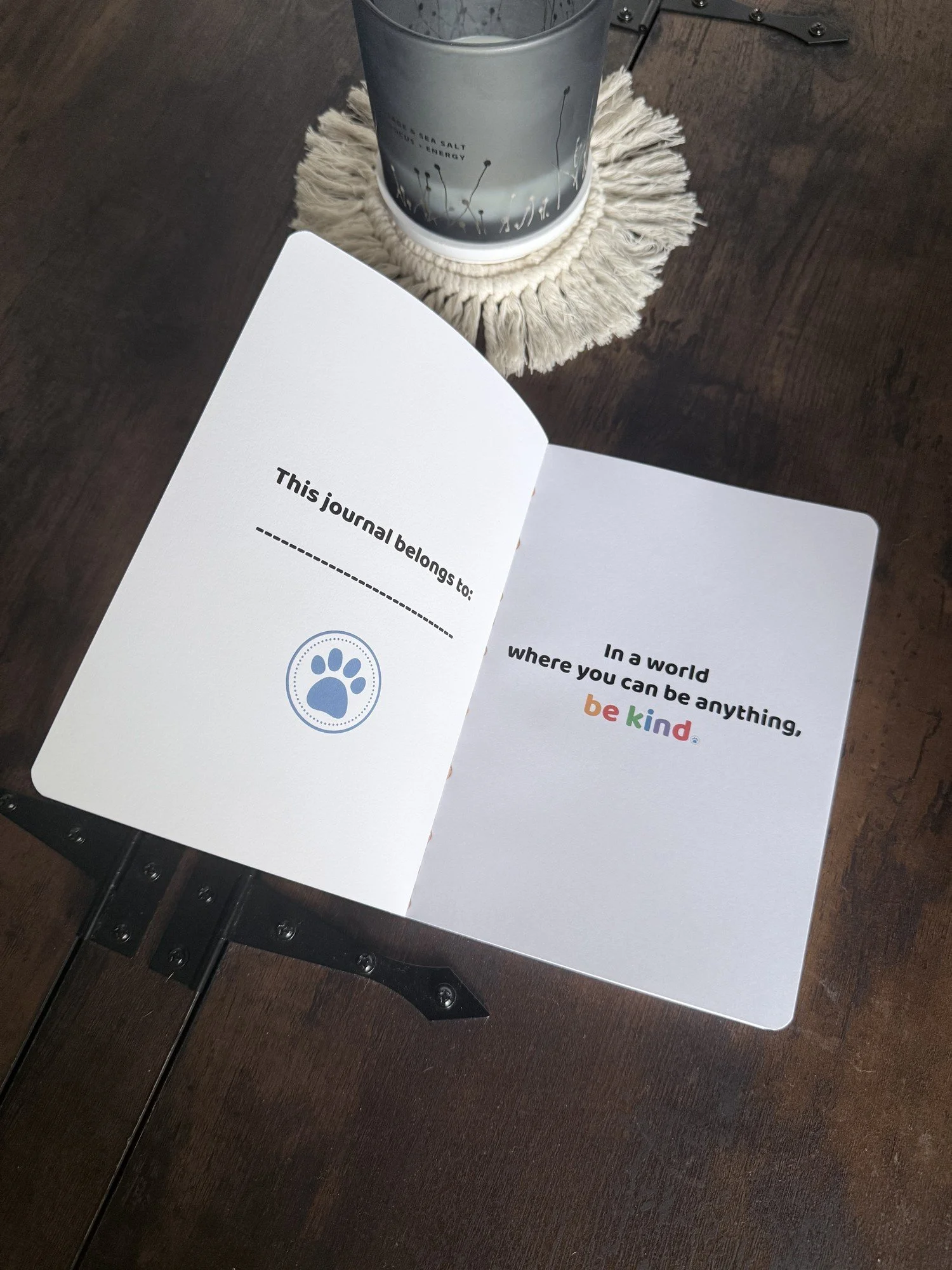Be Kind journal open to the inside cover — a "This journal belongs to" name line and blue paw print