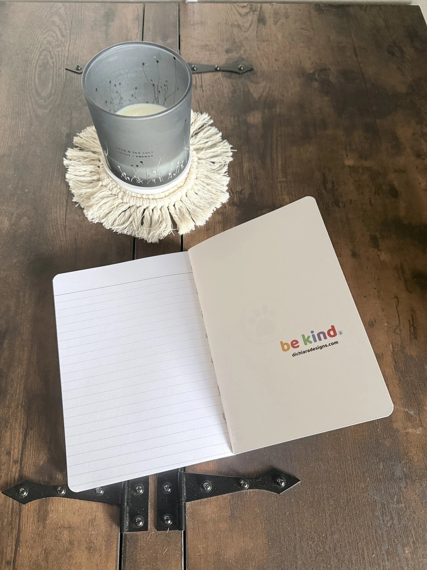 Be Kind journal open to lined pages, with the rainbow be kind wordmark and dichiaradesigns.com inside the back cover