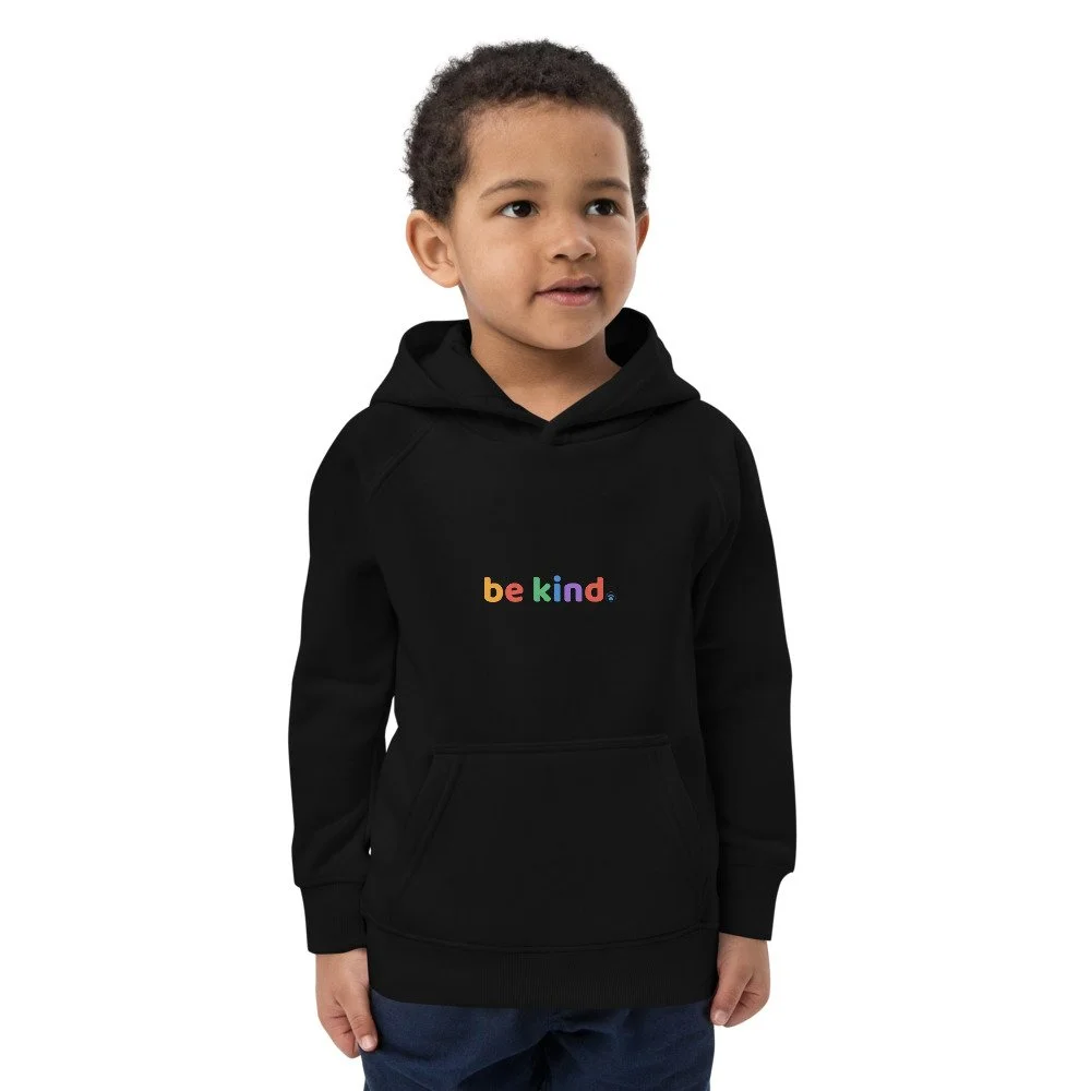 Young boy in a black be kind hoodie with the rainbow print across the chest