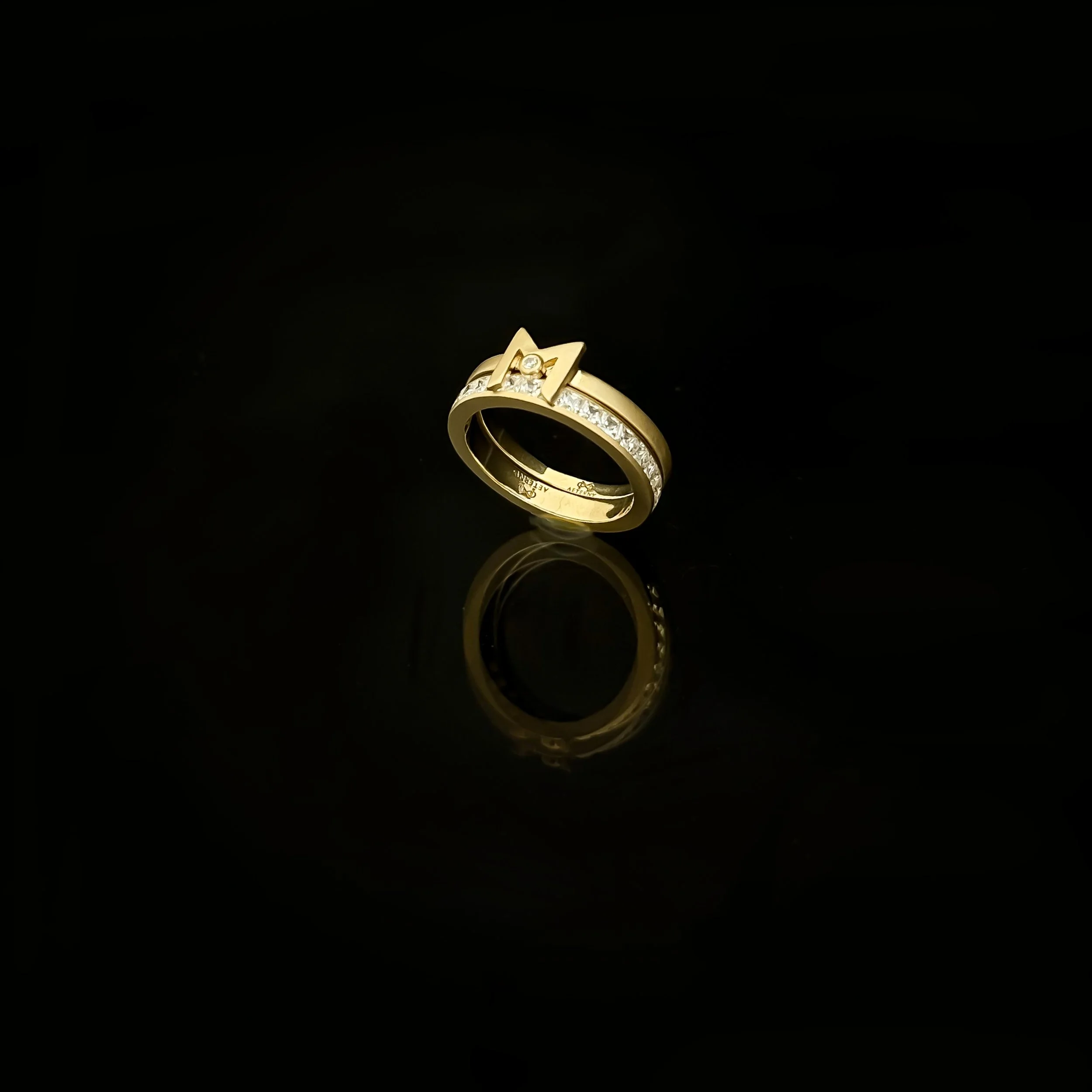 A gold ring with a star-shaped design containing small diamonds or gemstones, set against a black background.