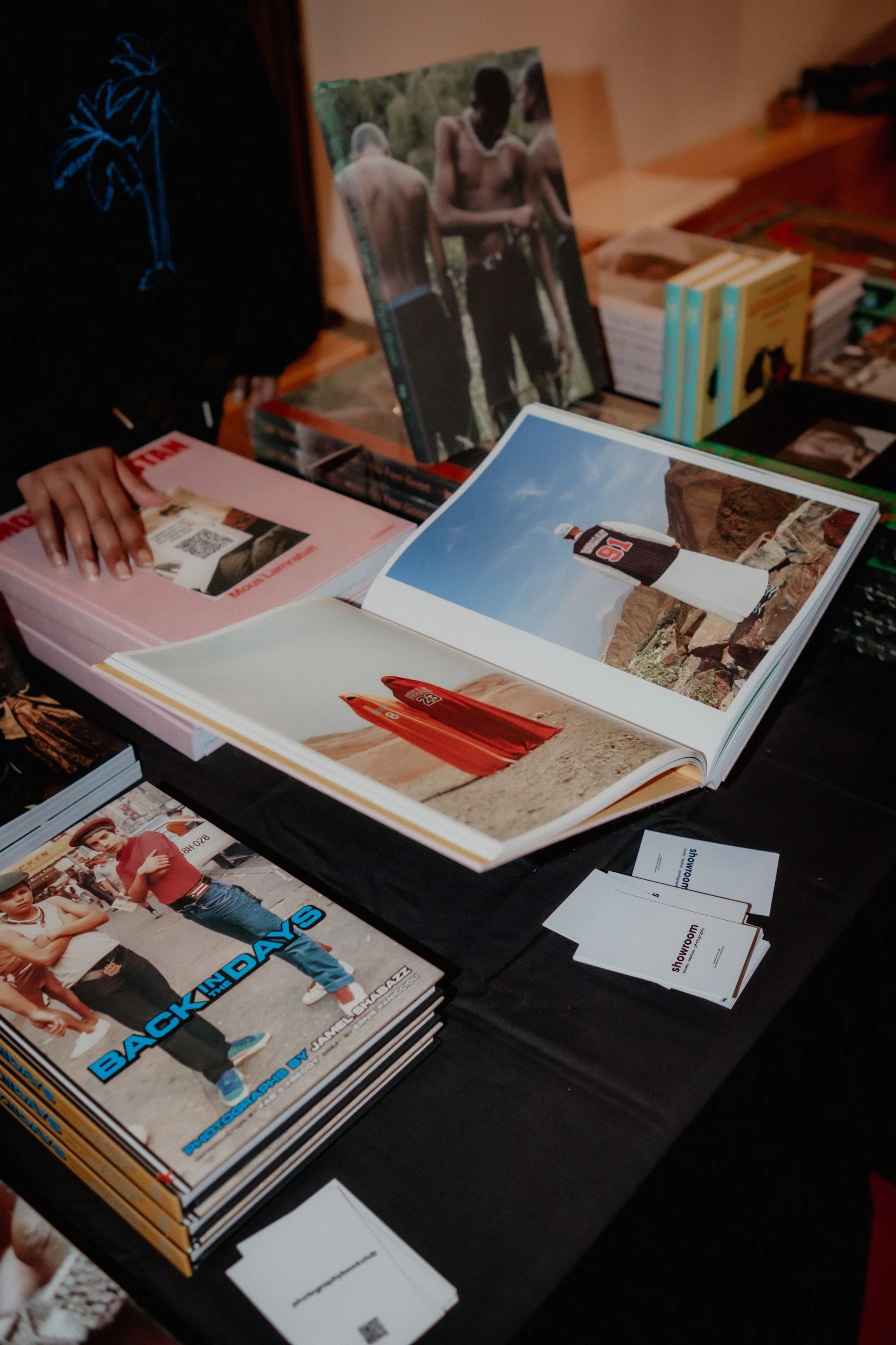 Various magazines and books displayed on tables, including a magazine opened to a page showing a beach scene with a person wearing a football jersey, and a magazine cover featuring people in casual clothing.