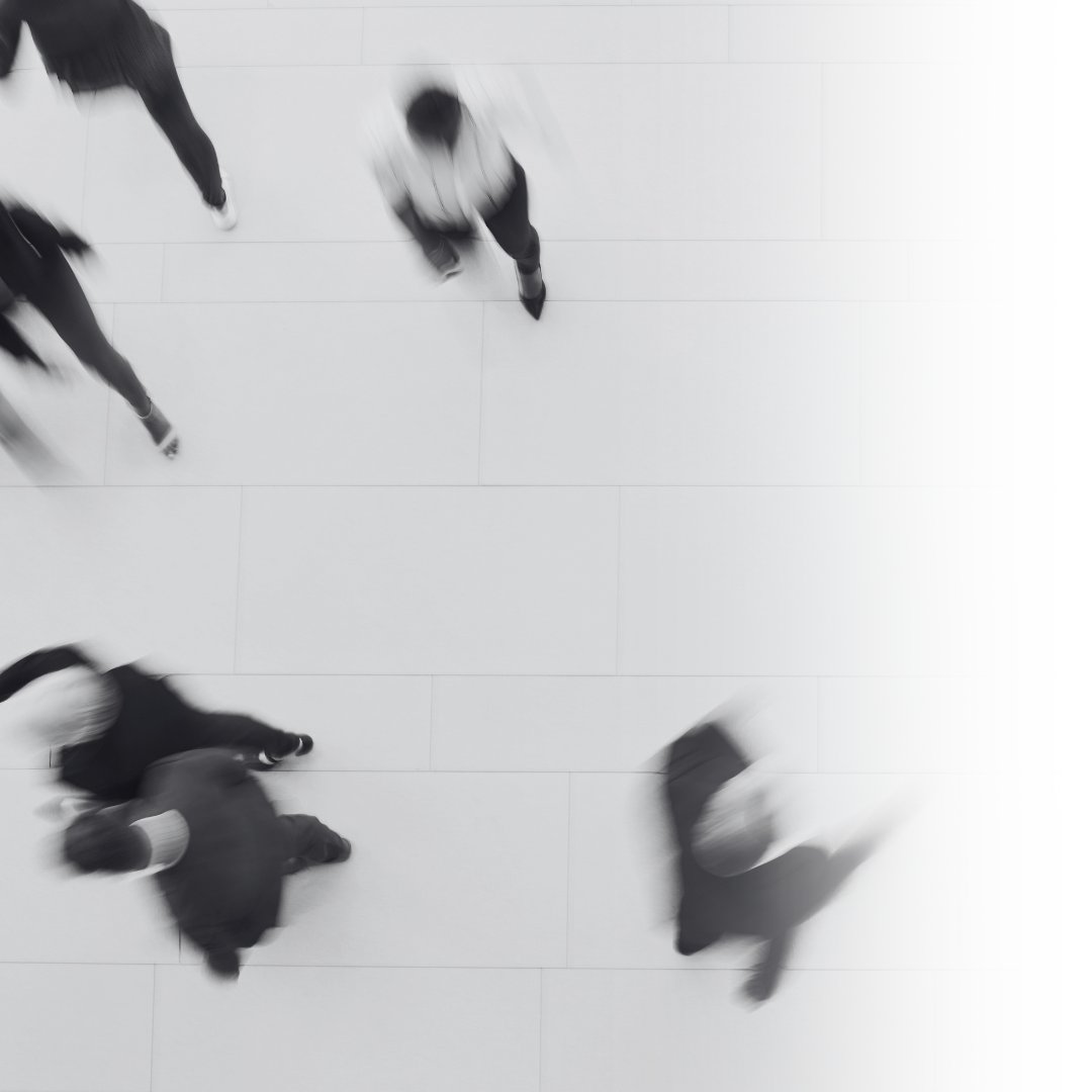 Blurred overhead view of six people walking on a tiled floor in a public space.