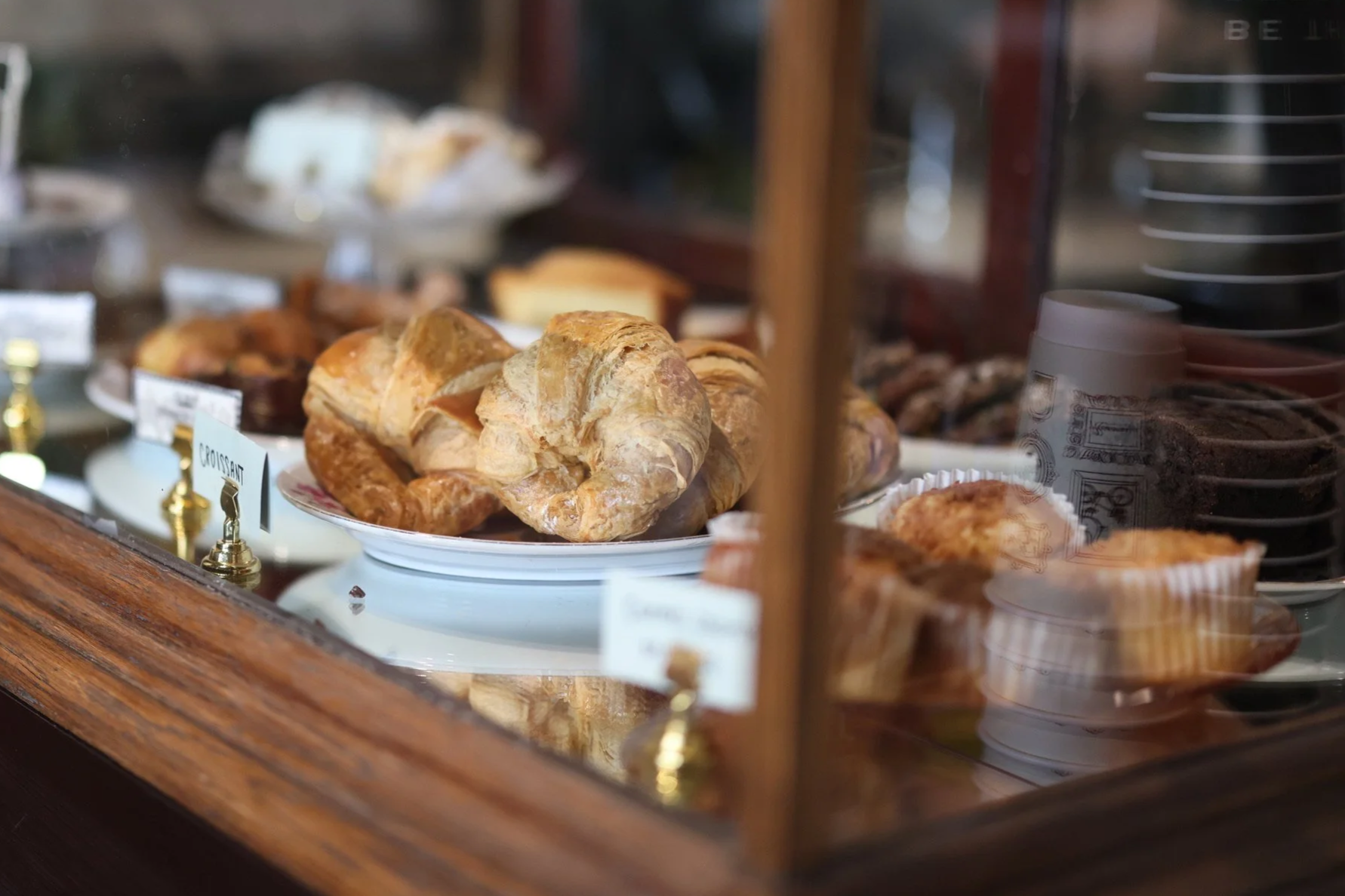 Croissants and other baked goods displayed behind glass at a bakery shop.