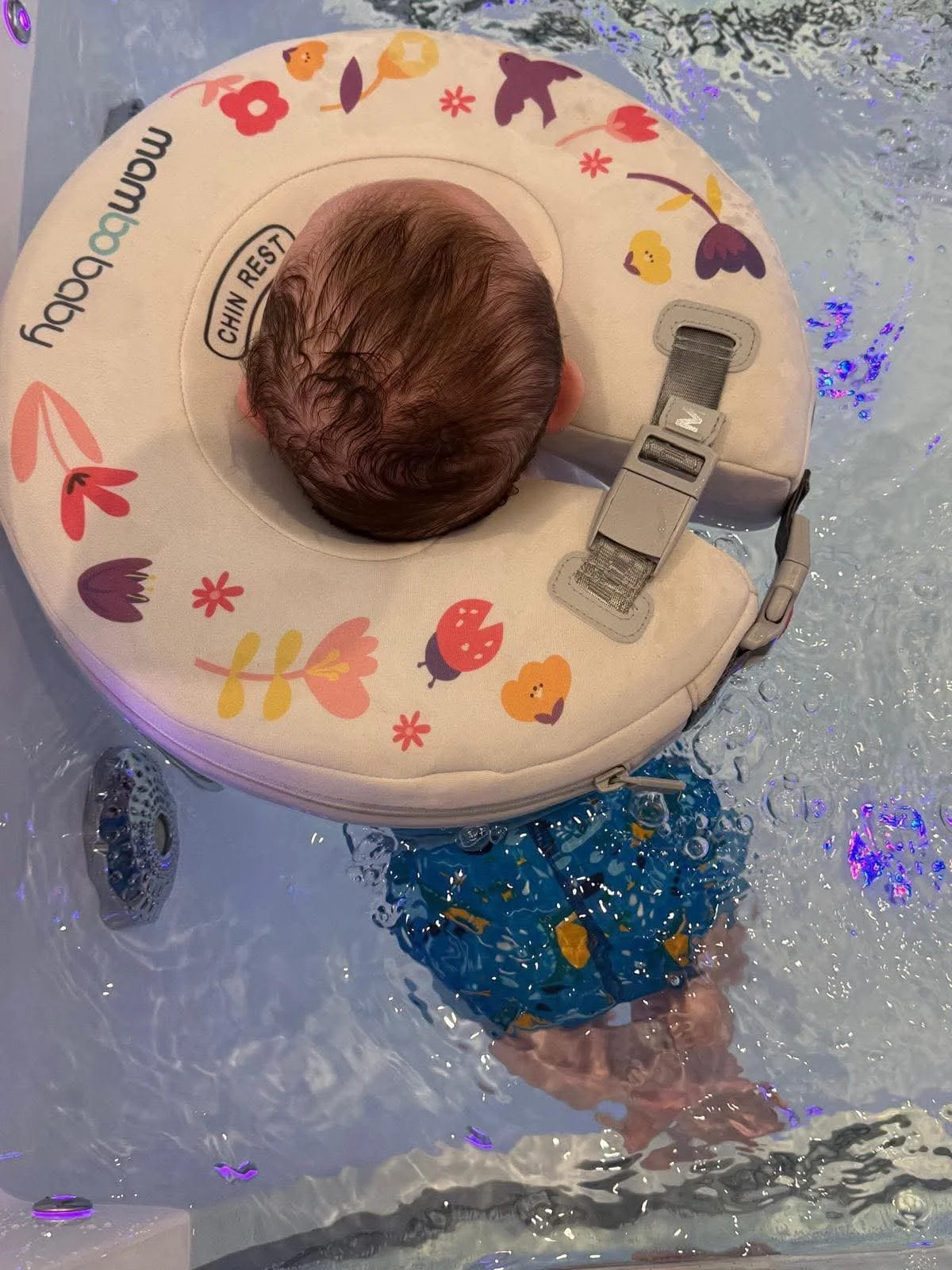 Top of a baby's head floating in the spa with a neck float