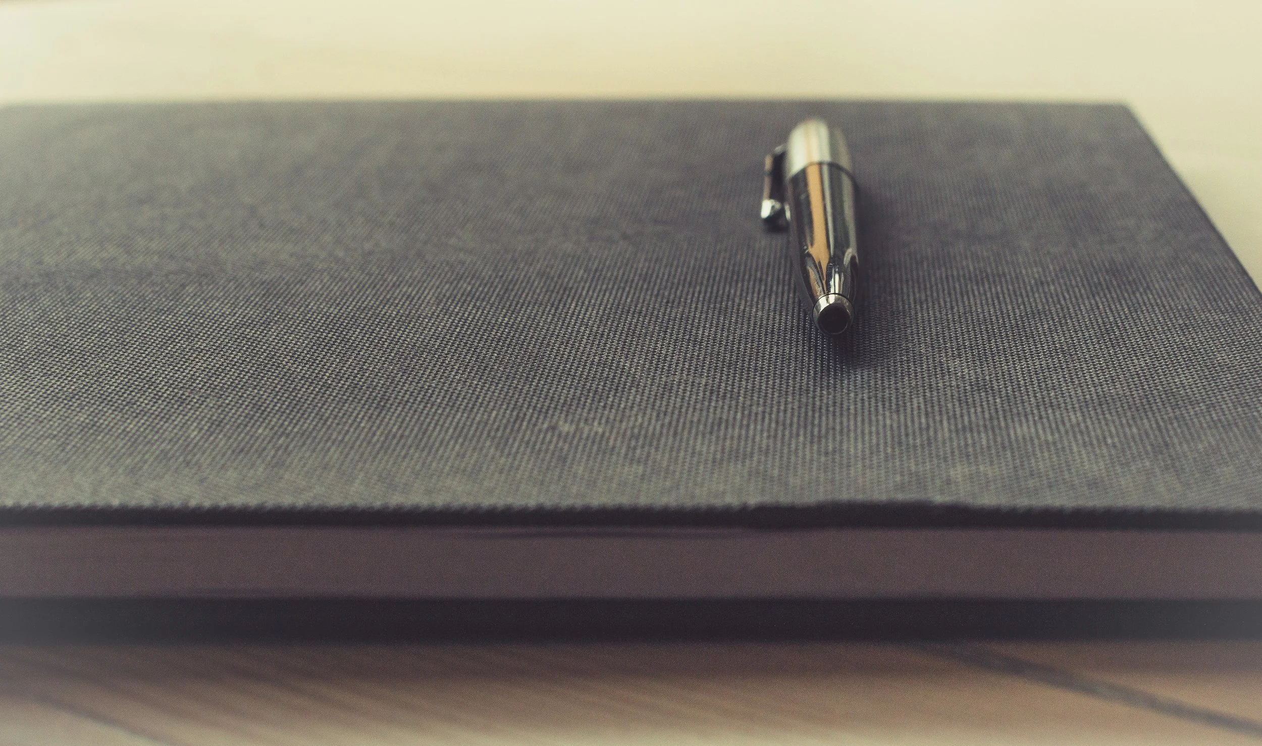 A pen sitting on top of a closed notepad
