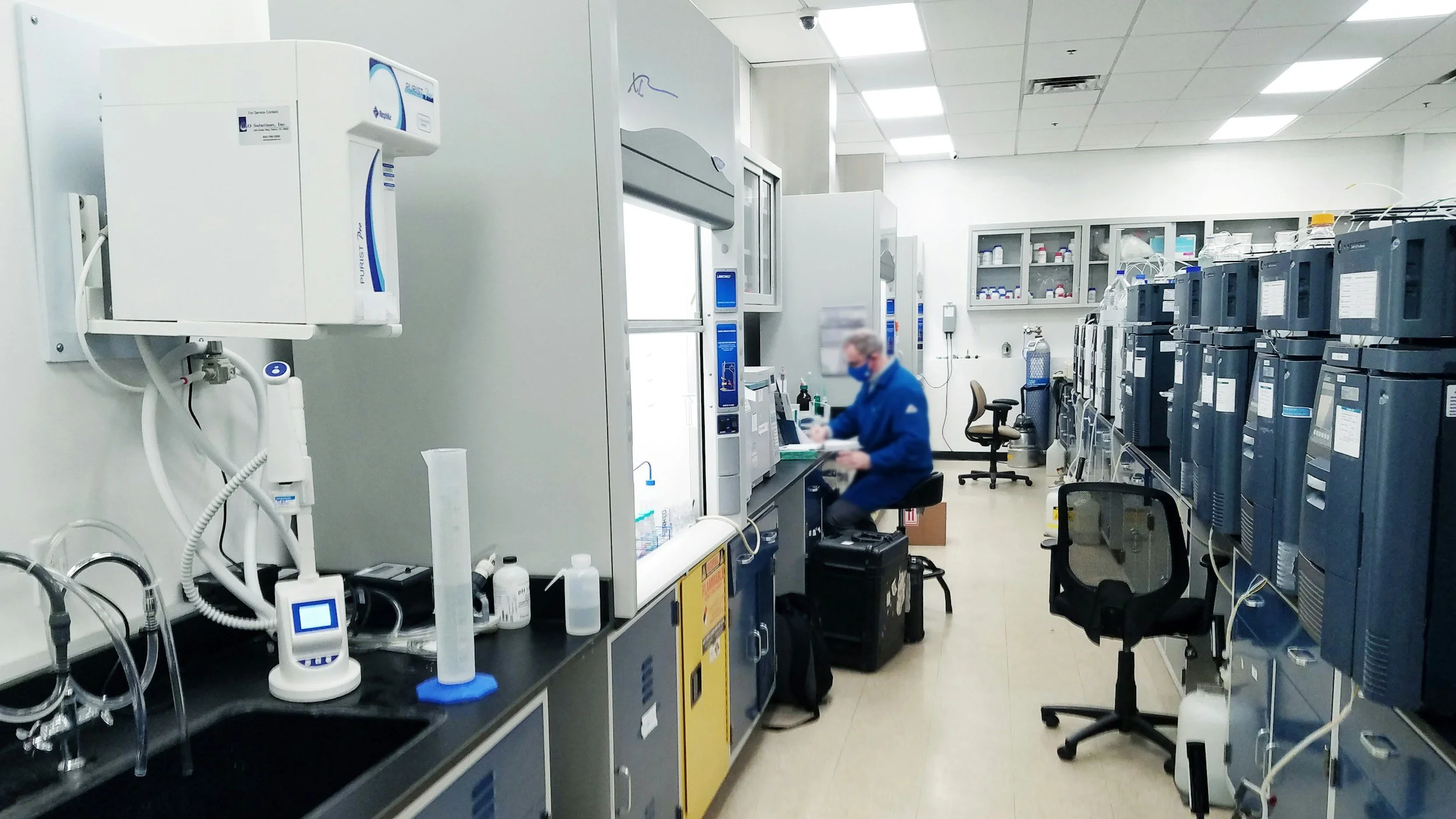 Laboratory with scientist working on a computer, surrounded by medical equipment, machines, and supplies.