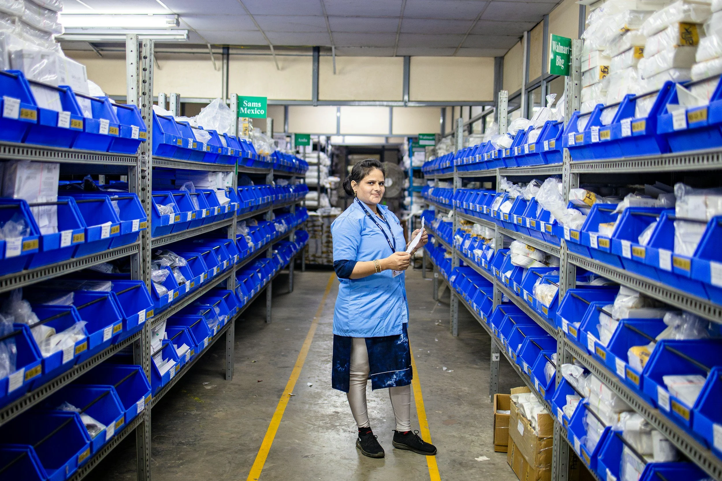 Female warehouse picker standing in an aisle selecting products for an order