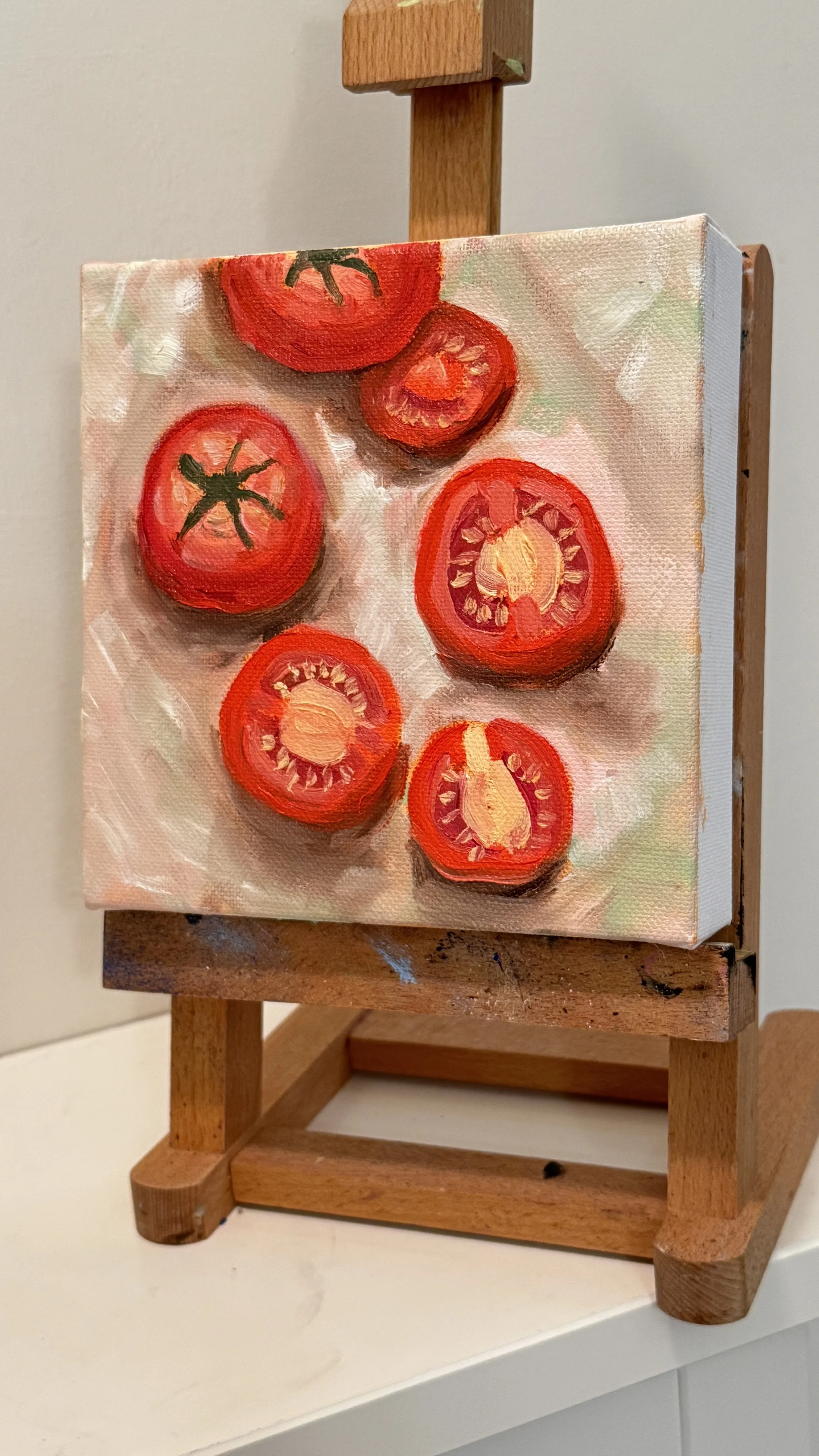 Painting of sliced tomatoes on a wooden easel.