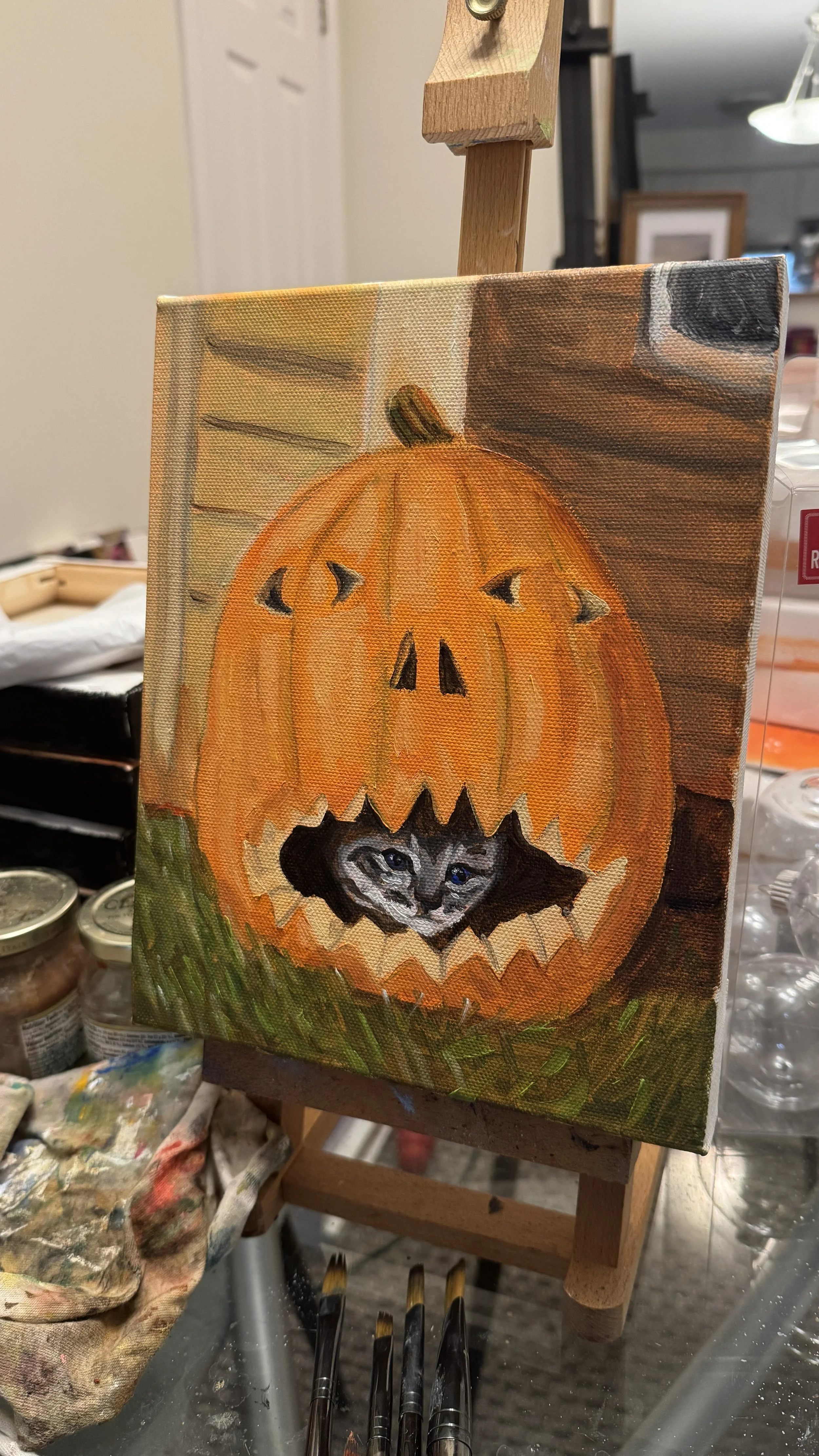 Jack the Cat, Oil on canvas, 8"x10" 2025. A painting of a carved pumpkin with a tabby kitten sitting inside. 
