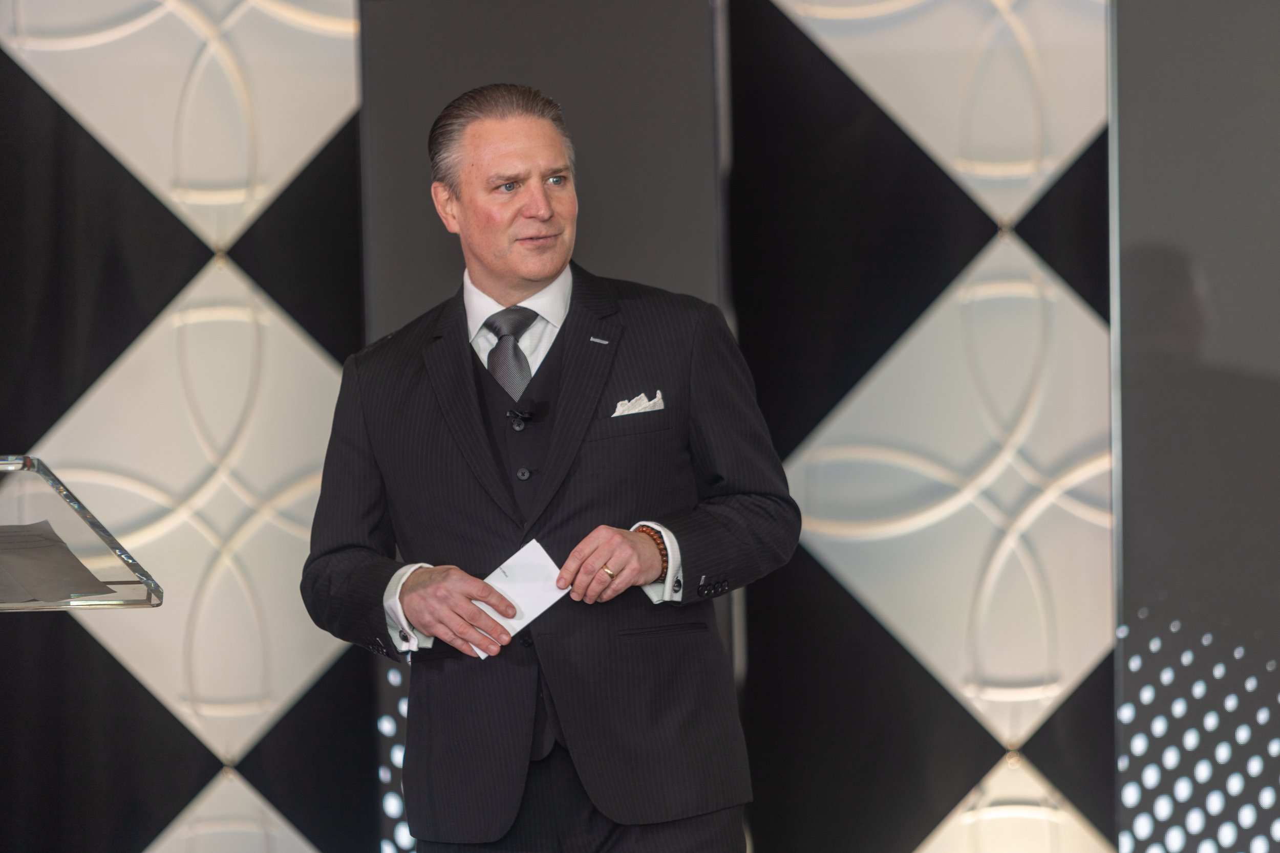 Corporate event photography capturing a speaker on stage presenting at a large business conference