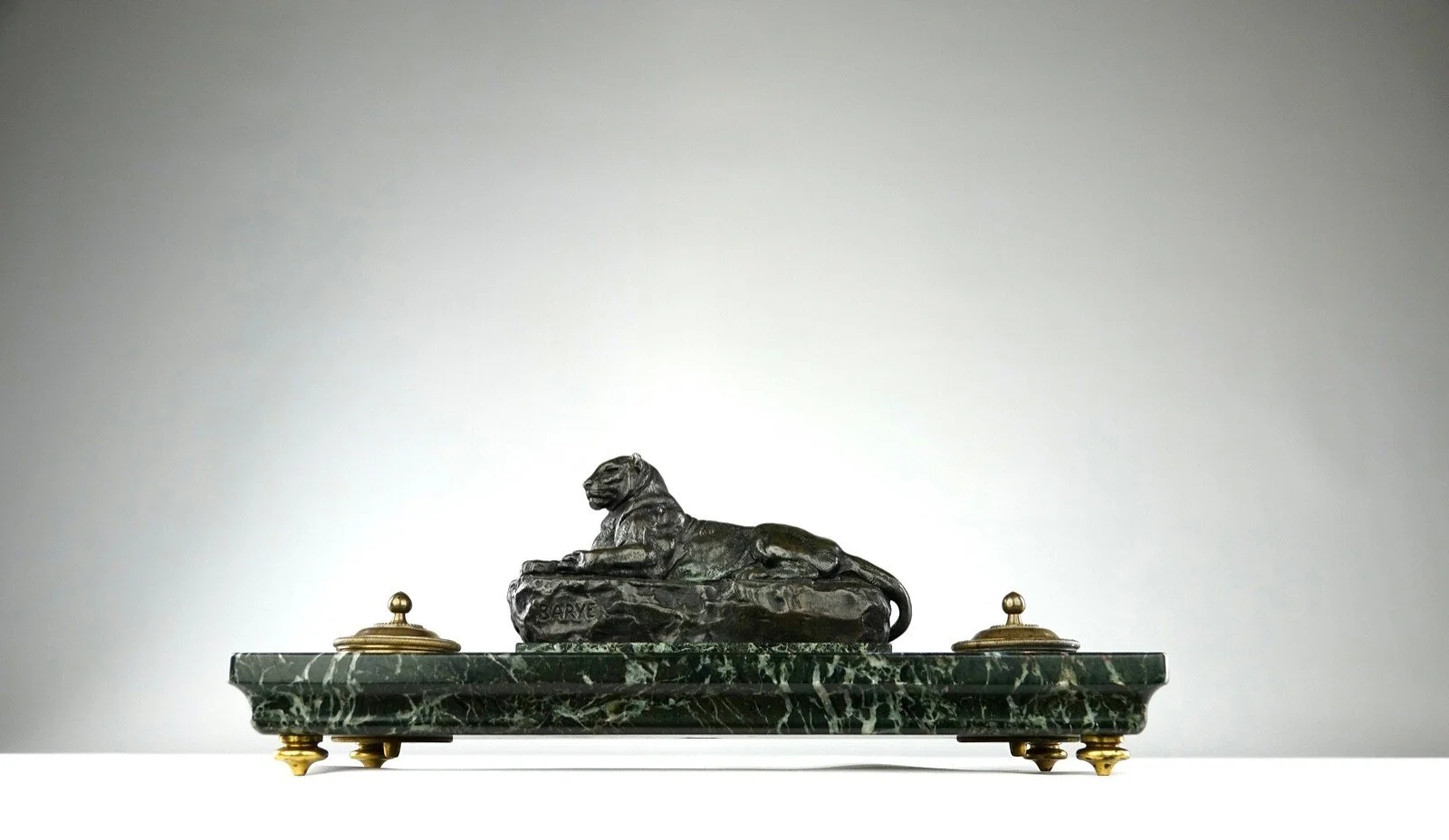 A bronze Lionel the Lion sculpture on a green marble base with gold accents.