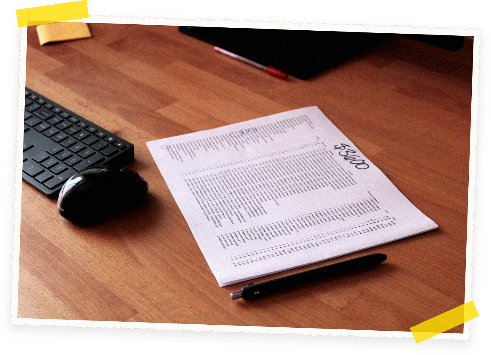 Keyboard, mouse, and pen beside a printed keyword and cost report on a wooden desk at Web Works Marketing, taped like a scrapbook photo.