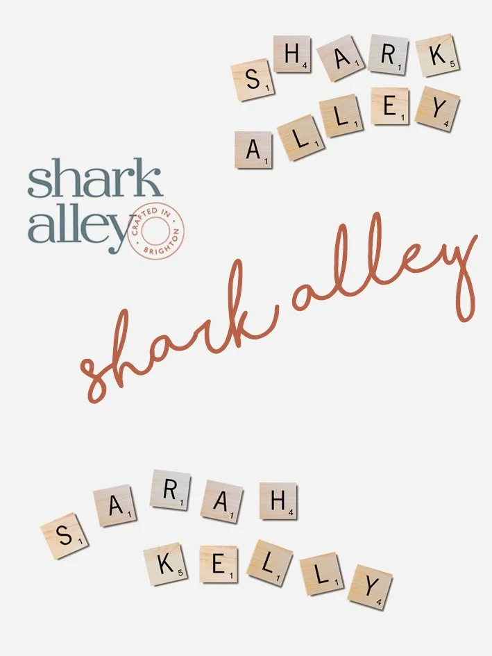 Scrabble tiles spelling out 'SHARK,' 'ALLEY,' 'SARAH,' and 'KELLY,' with logos for 'Shark Alley' and 'Brighton, crafted in Brighton' on a white background.