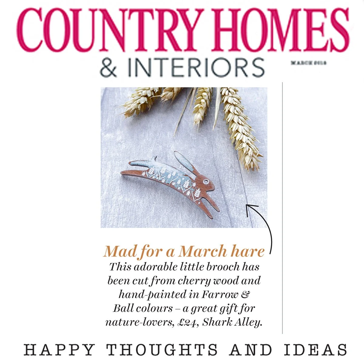 Cover of Country Homes & Interiors magazine featuring a decorative March hare brooch made from cherry wood, adorned with painted floral designs, placed with dried wheat stalks on a wooden surface.