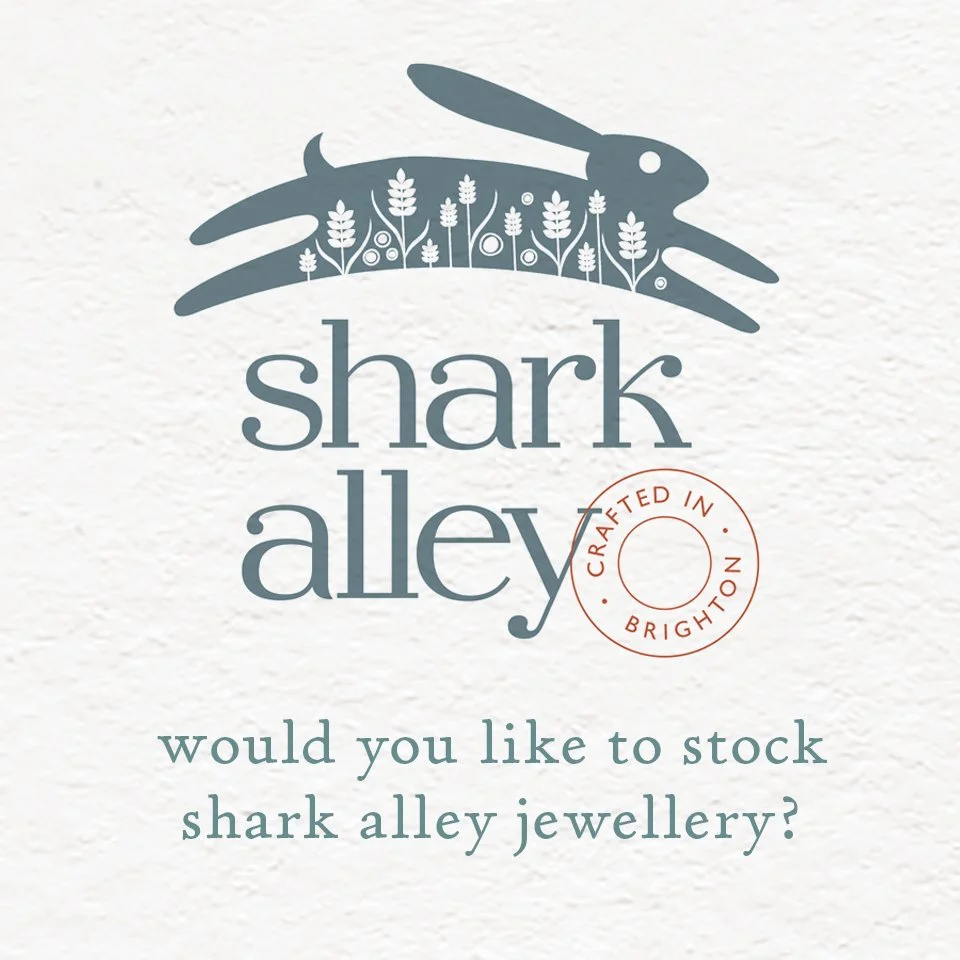 Promotional flyer for Shark Alley jewellery, featuring a stylized rabbit over a field of flowers. The flyer asks, 'would you like to stock shark alley jewellery?' and indicates it is crafted in Brighton.