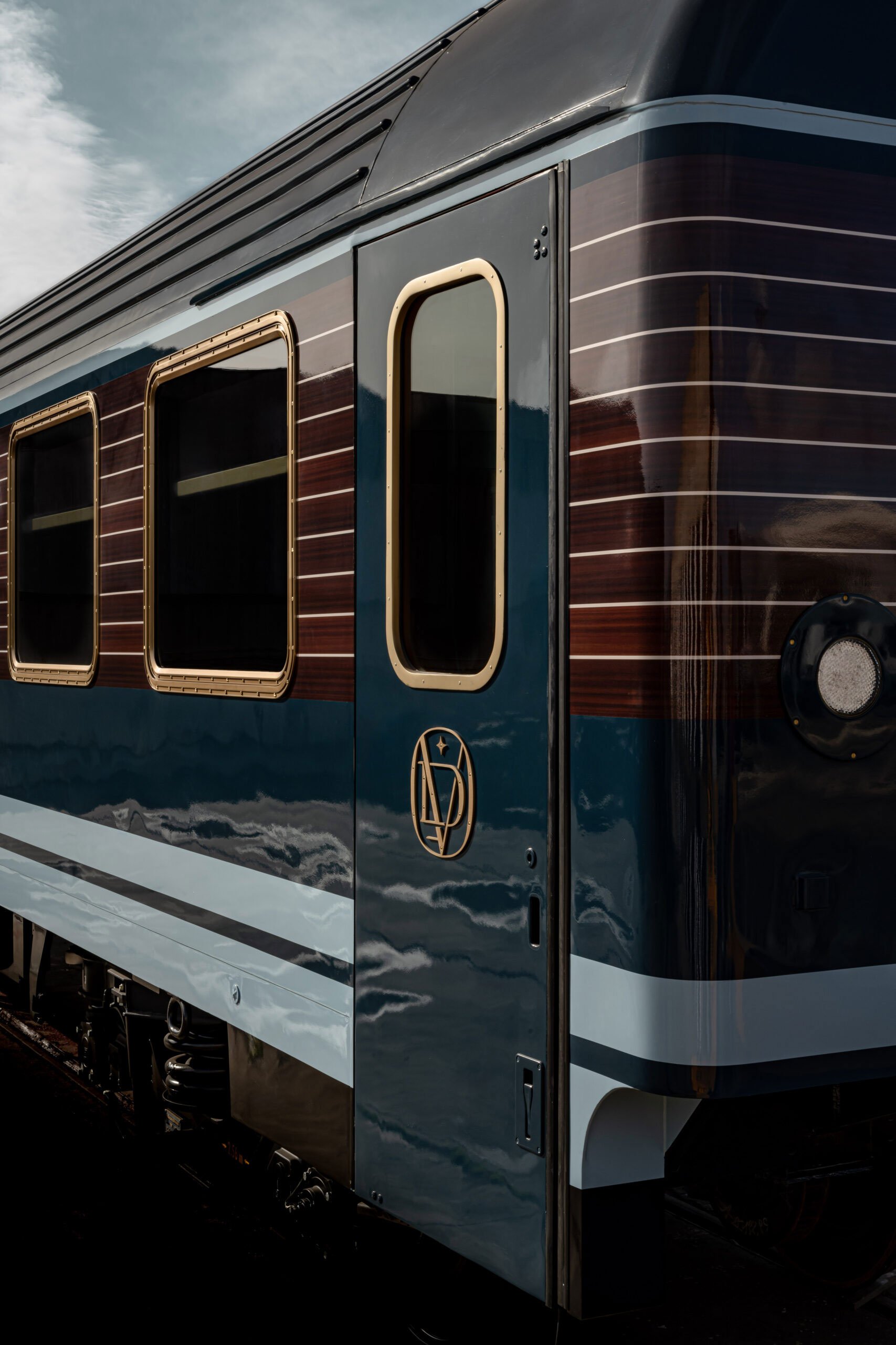 Close-up of a vintage train with a dark polished exterior and gold-accented window frames, featuring a logo on the side.