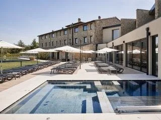 Outdoor swimming pool area with lounge chairs and umbrellas next to a modern building.