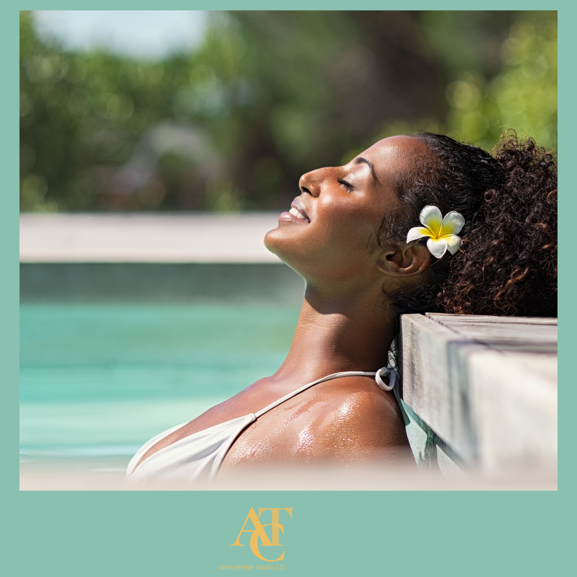 A woman relaxing outdoors with her eyes closed, a white flower in her curly hair, shining skin, and a background of greenery and blurred natural scenery.