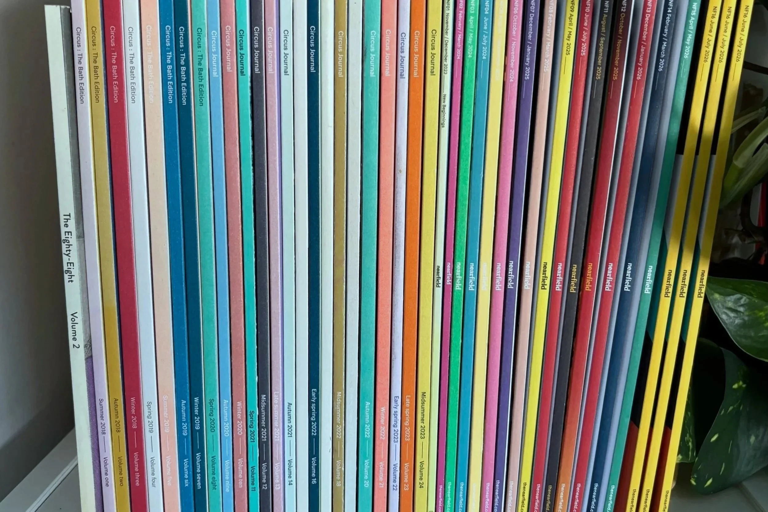 Colourful books on a shelf, including copies of Circus Journal and nearfield magazine dating from 2018 to 2026