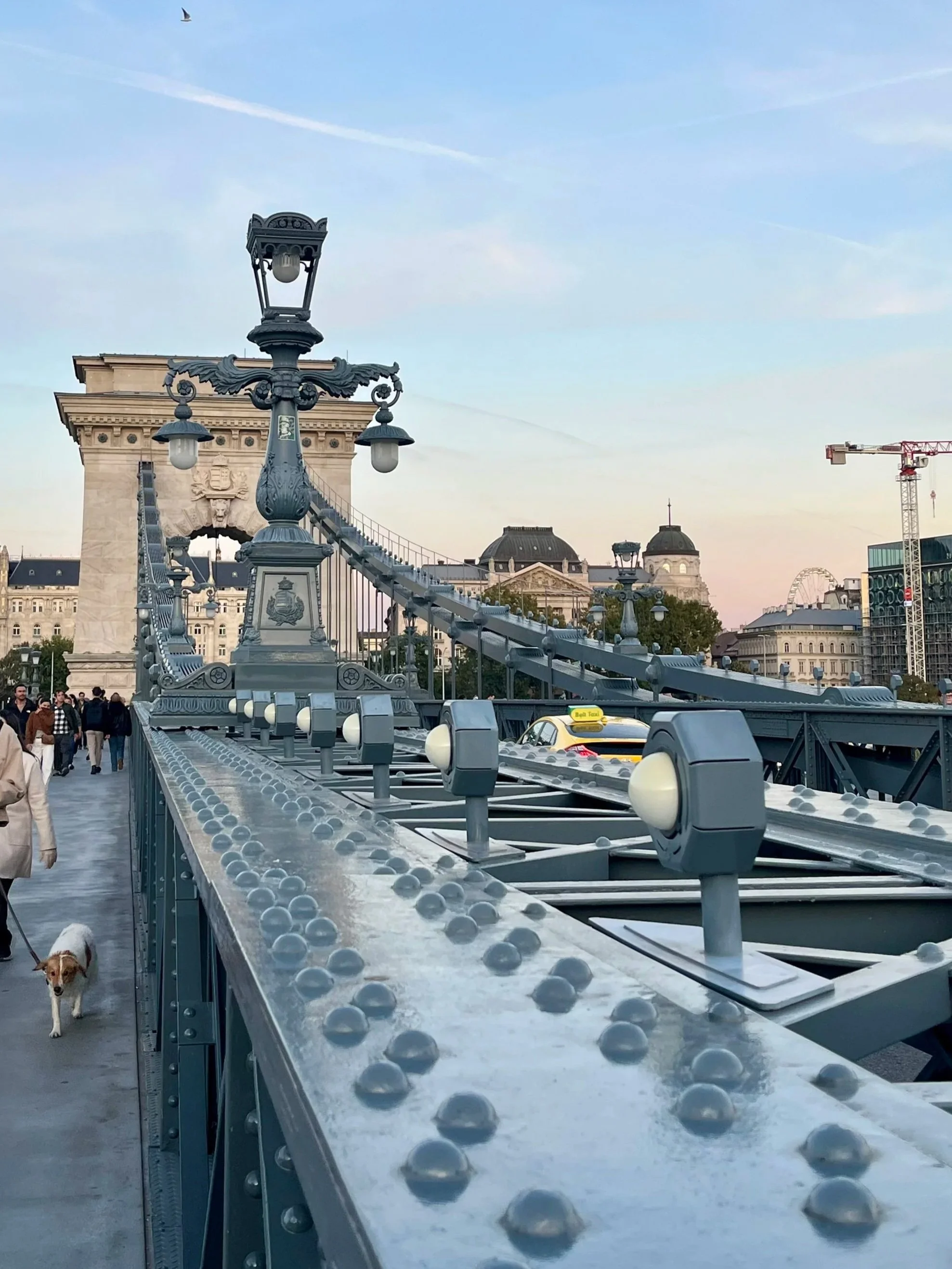 walkway on the historic Széchenyi Chain Bridge in Budapest under a clear evening sky.