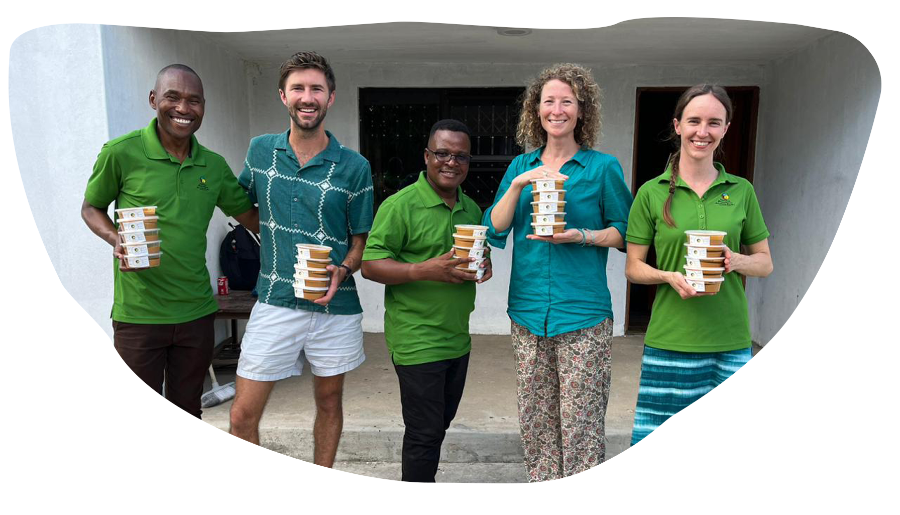 Group of five people standing outside, holding bowls of food and smiling.