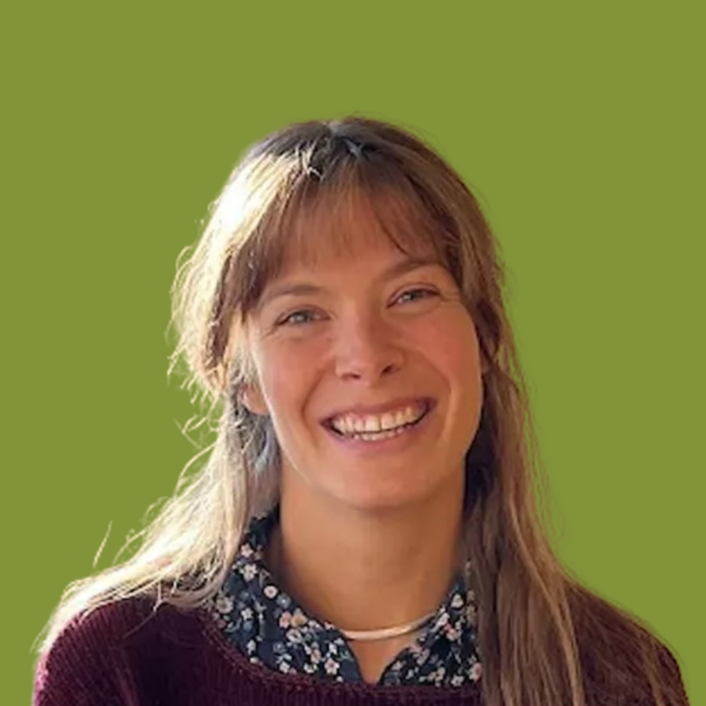 A woman with long, light brown hair smiling against a green background.