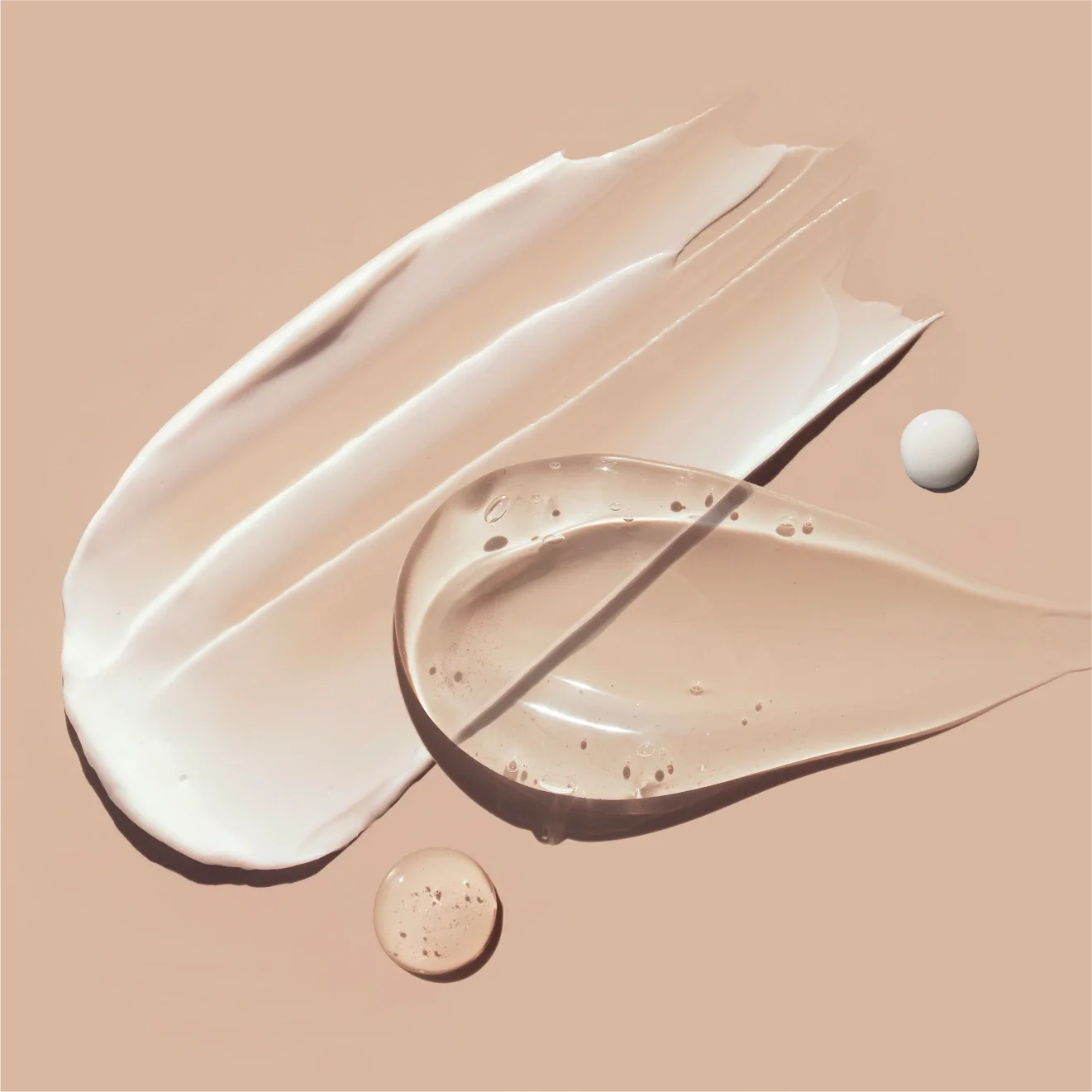 Cosmetic smears of creamy texture on a pastel beige background