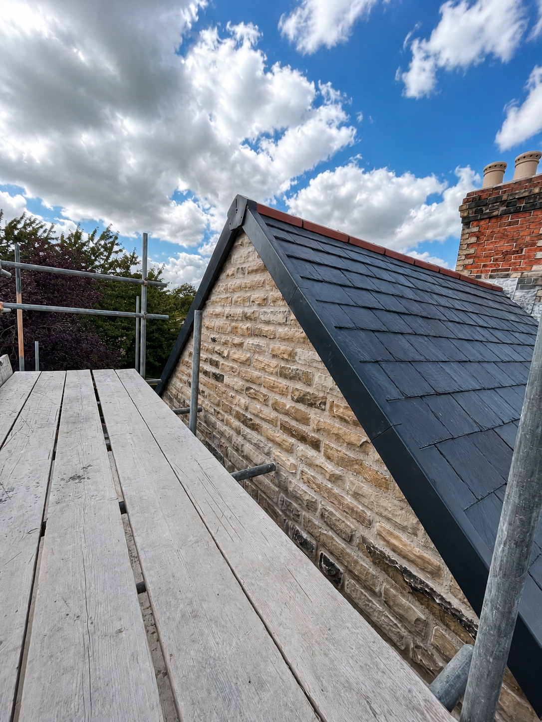 Newly installed natural slate roof and stone gable during the extension build.