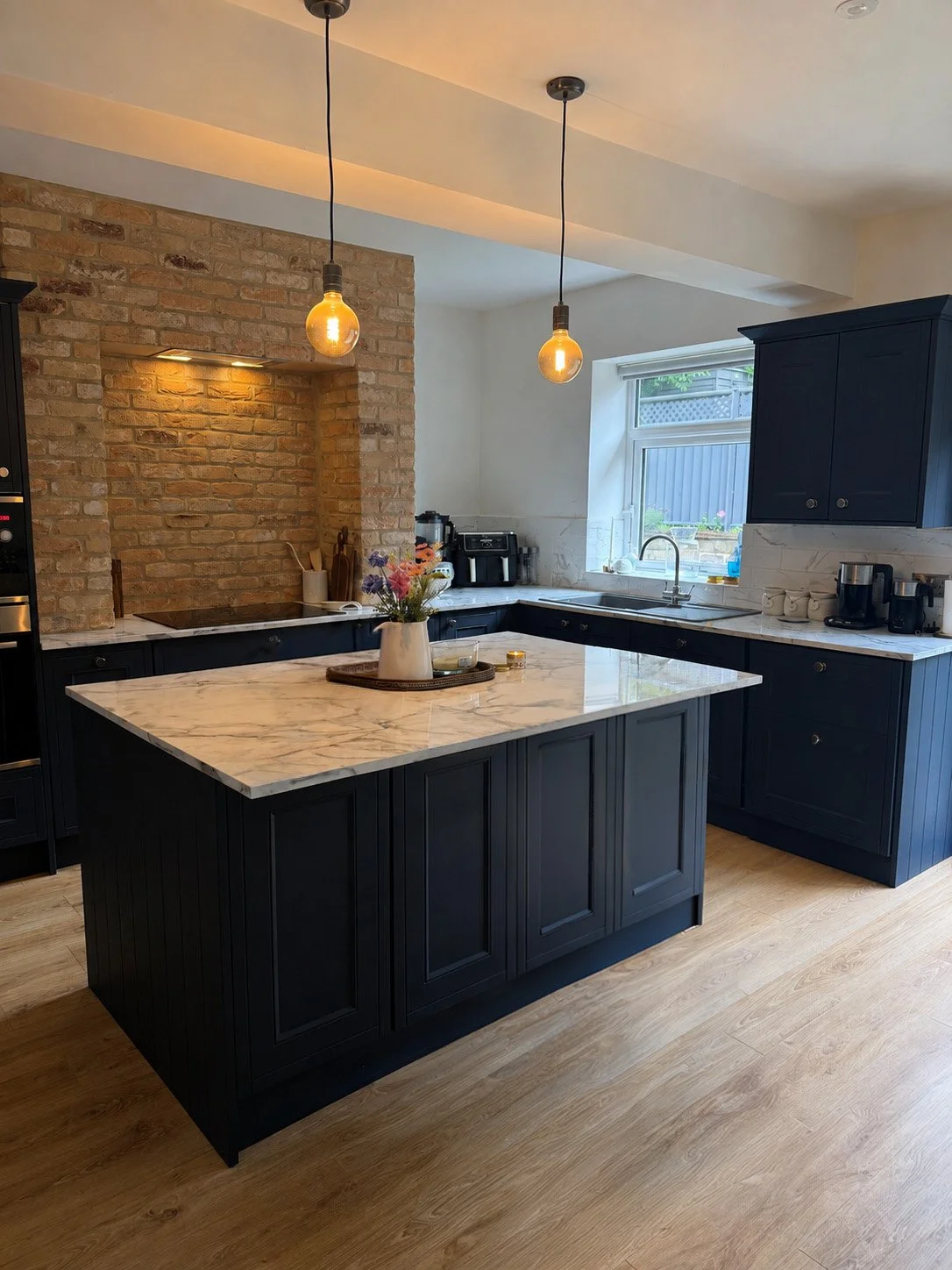 Completed kitchen refurbishment featuring exposed brickwork, shaker cabinetry and marble effect worktops.