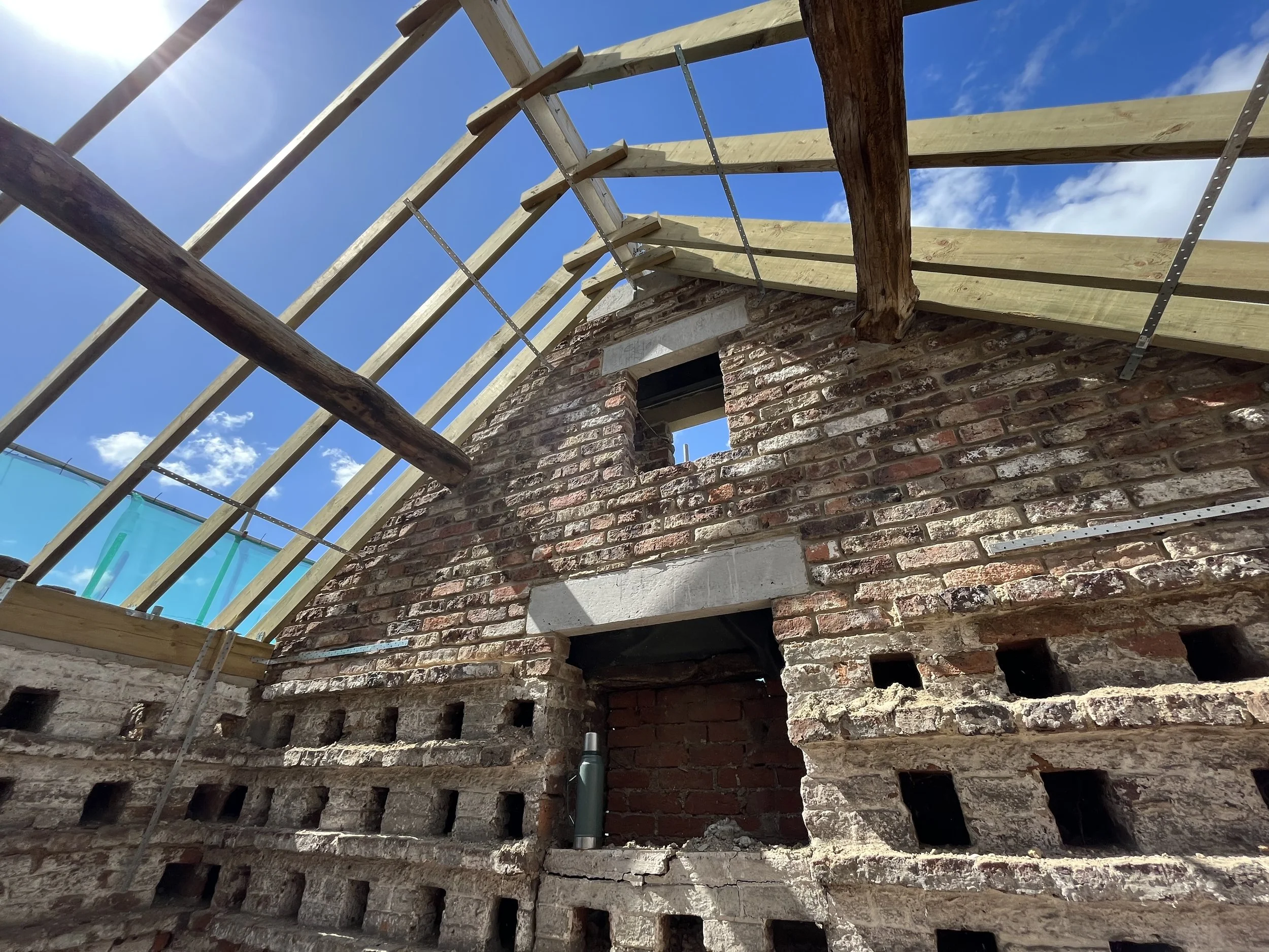 Heritage roof structure during restoration with original brickwork and new timber roof construction.