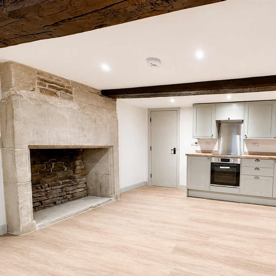 Renovated kitchen within a traditional property featuring restored stone fireplace and exposed timber beam.